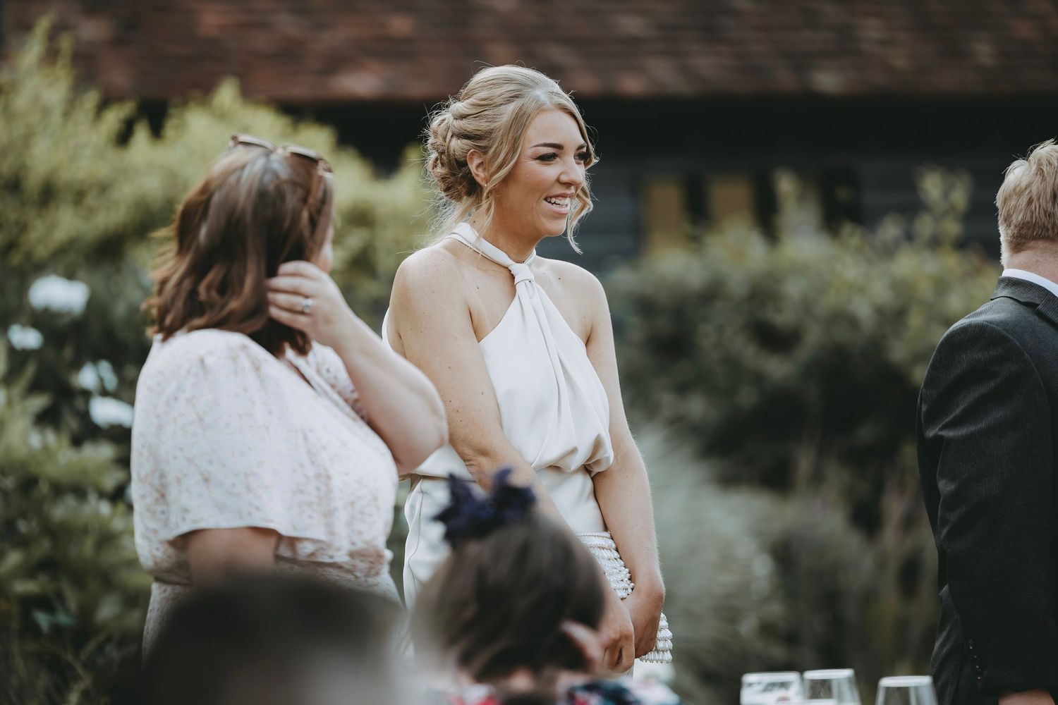 Outdoor wedding celebration with guests mingling in natural lighting.
