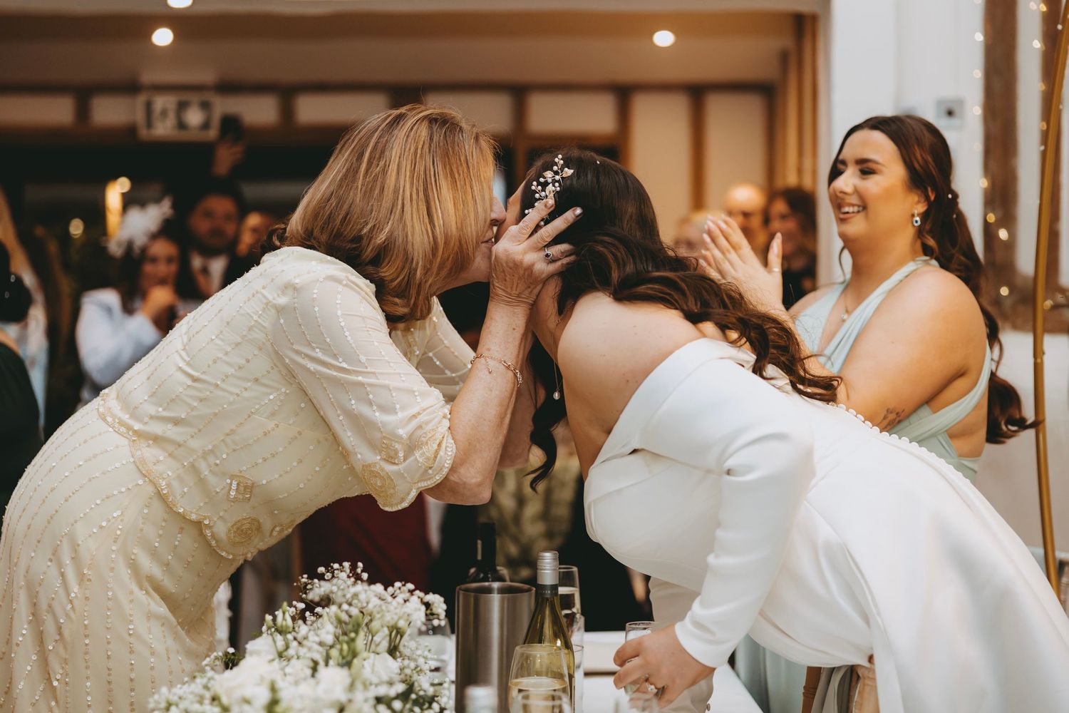 Emotional wedding reception moment between guests at decorated dining table.