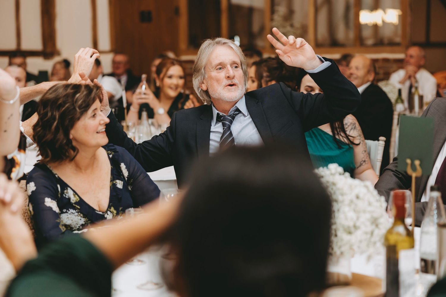 Wedding reception guests raise their hands in celebration during festivities.