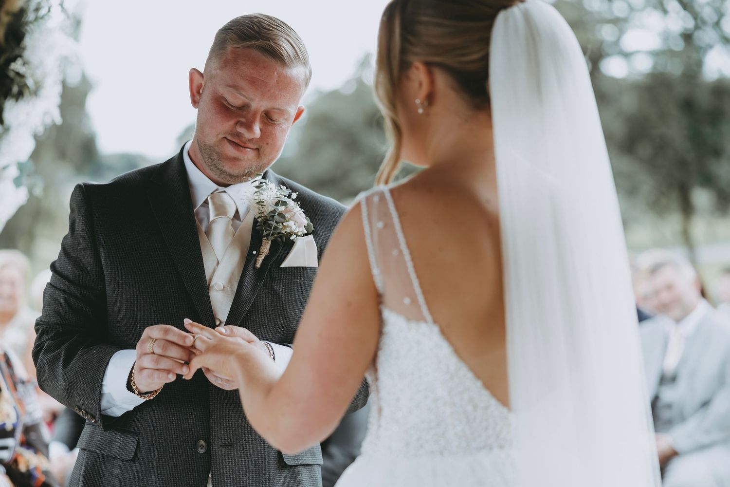 Couple exchanging rings during intimate garden wedding ceremony.