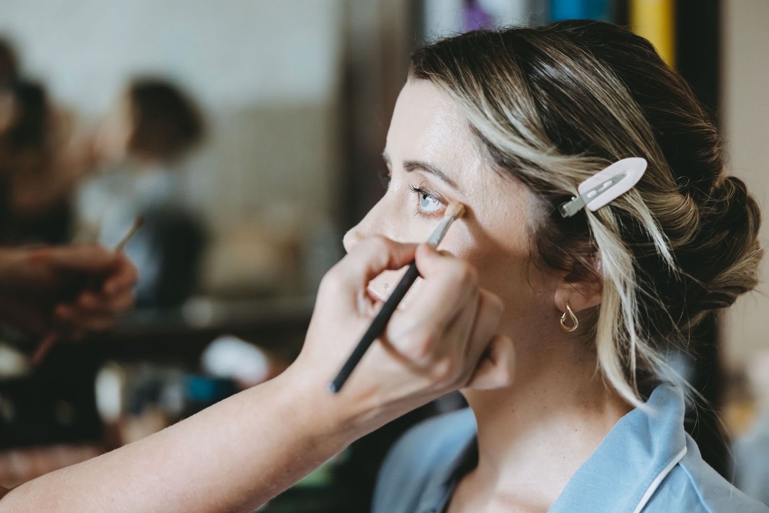 Professional makeup artists applying cosmetics during bridal preparation.