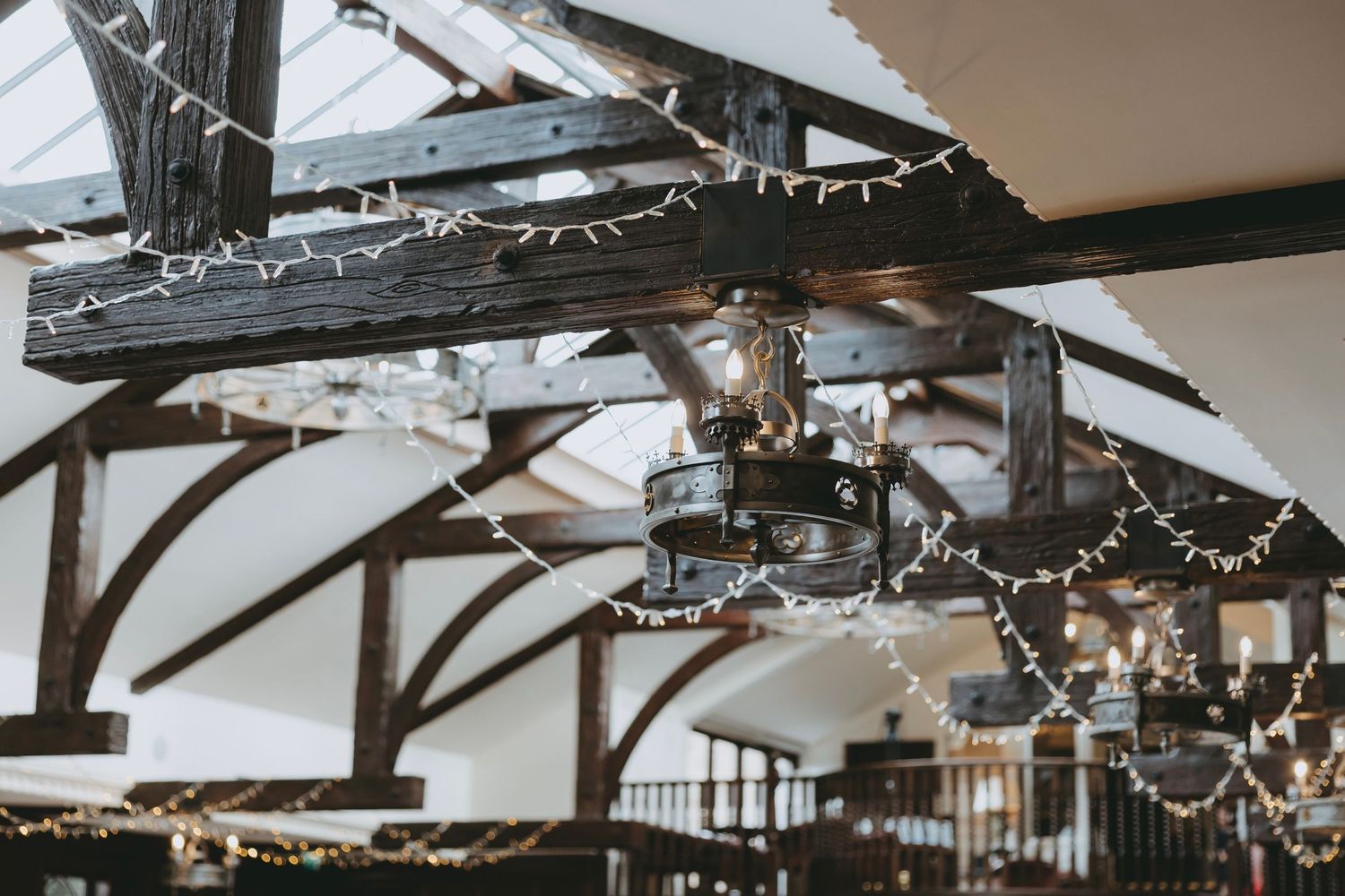 Exposed wooden beams with string lights create a romantic wedding venue atmosphere.