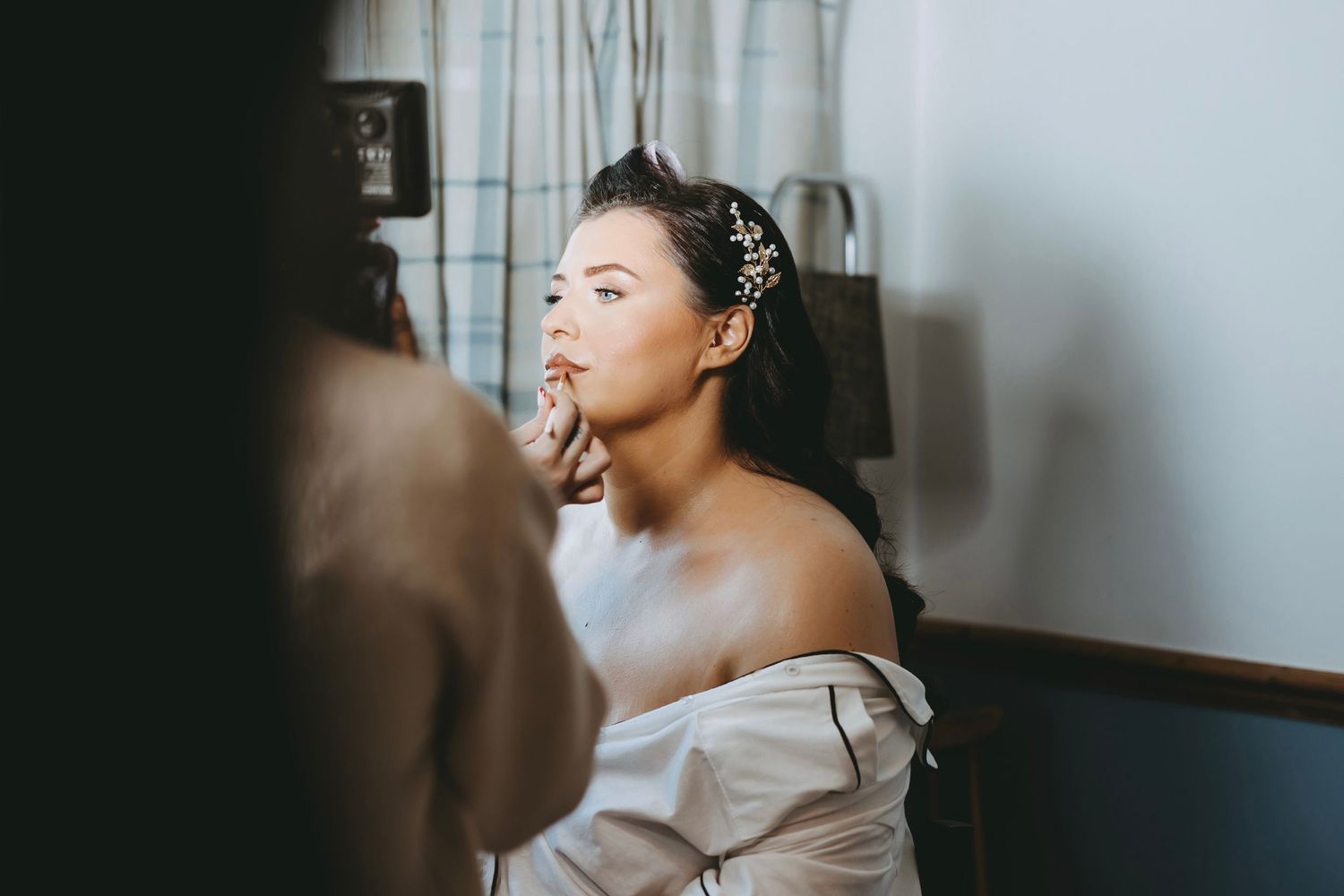 Professional makeup artist applying cosmetics during bridal preparation.