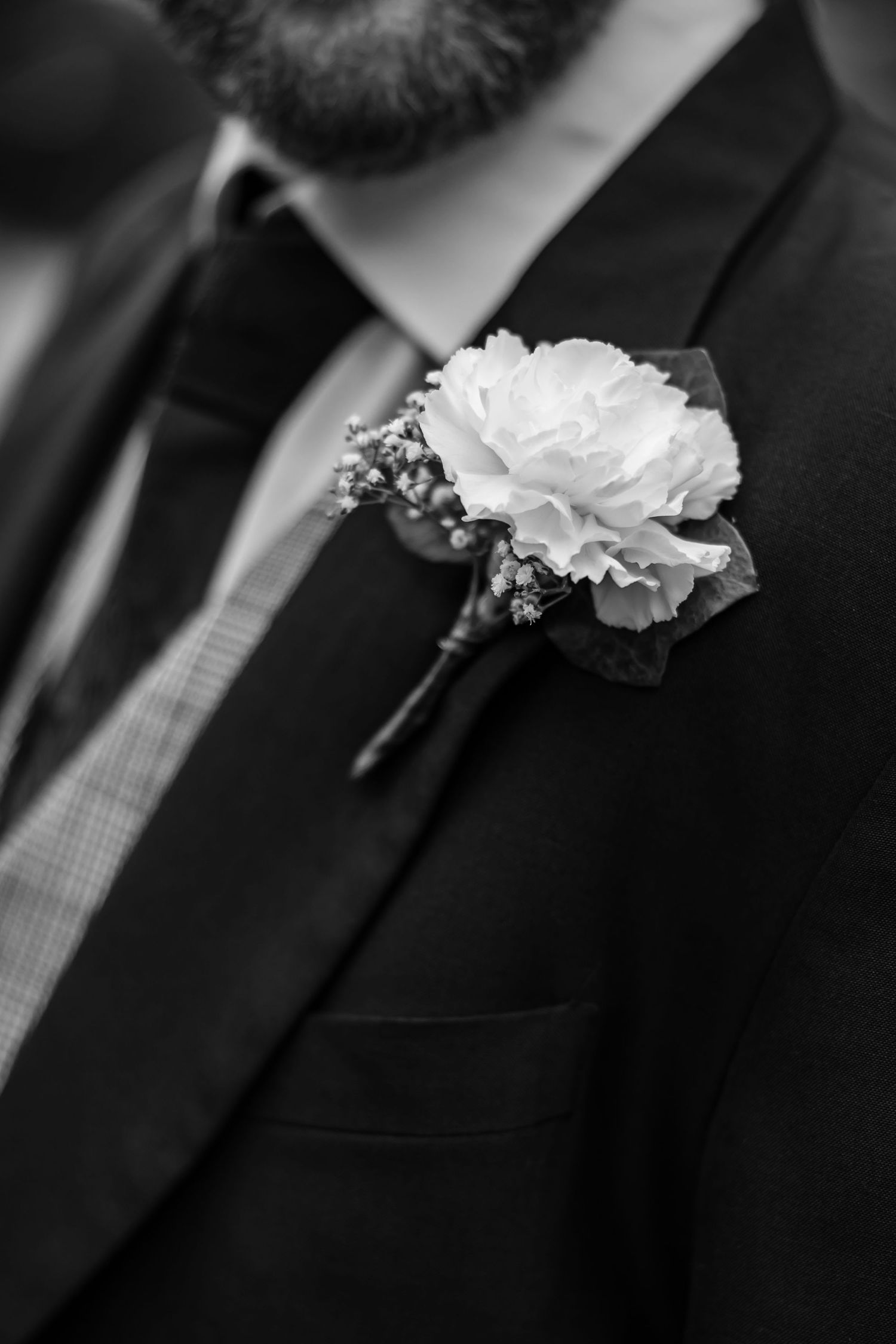 Close-up of white boutonniere on black suit lapel.