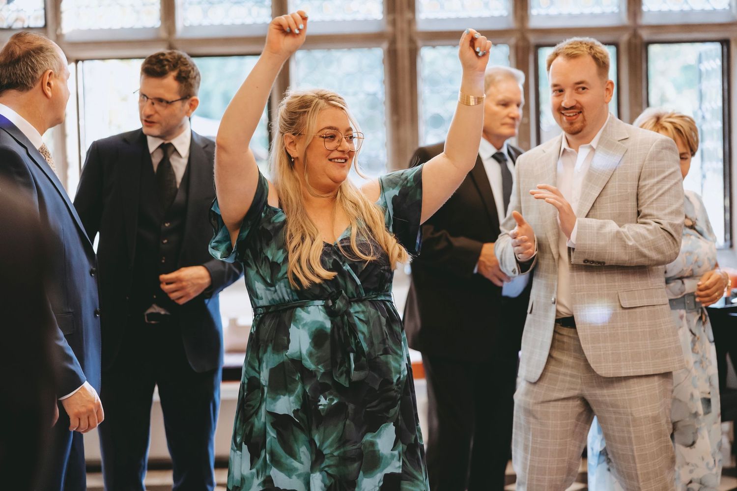 Wedding guests laughing and dancing together at an elegant indoor reception.