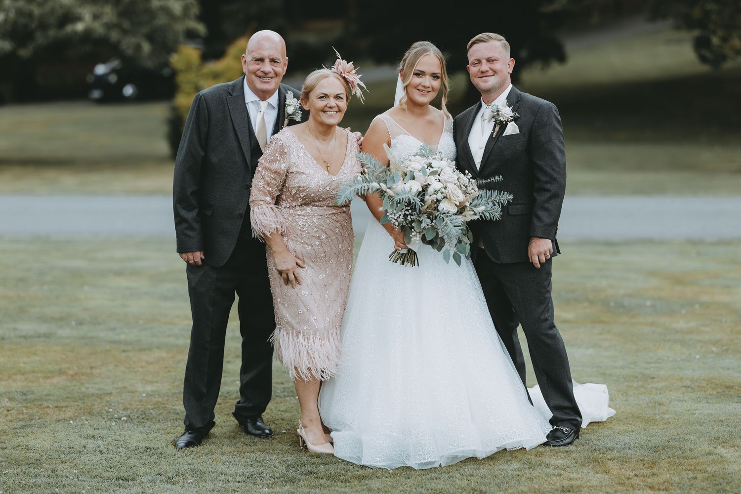 Small group of wedding attendees gathered for intimate formal photos outdoors.