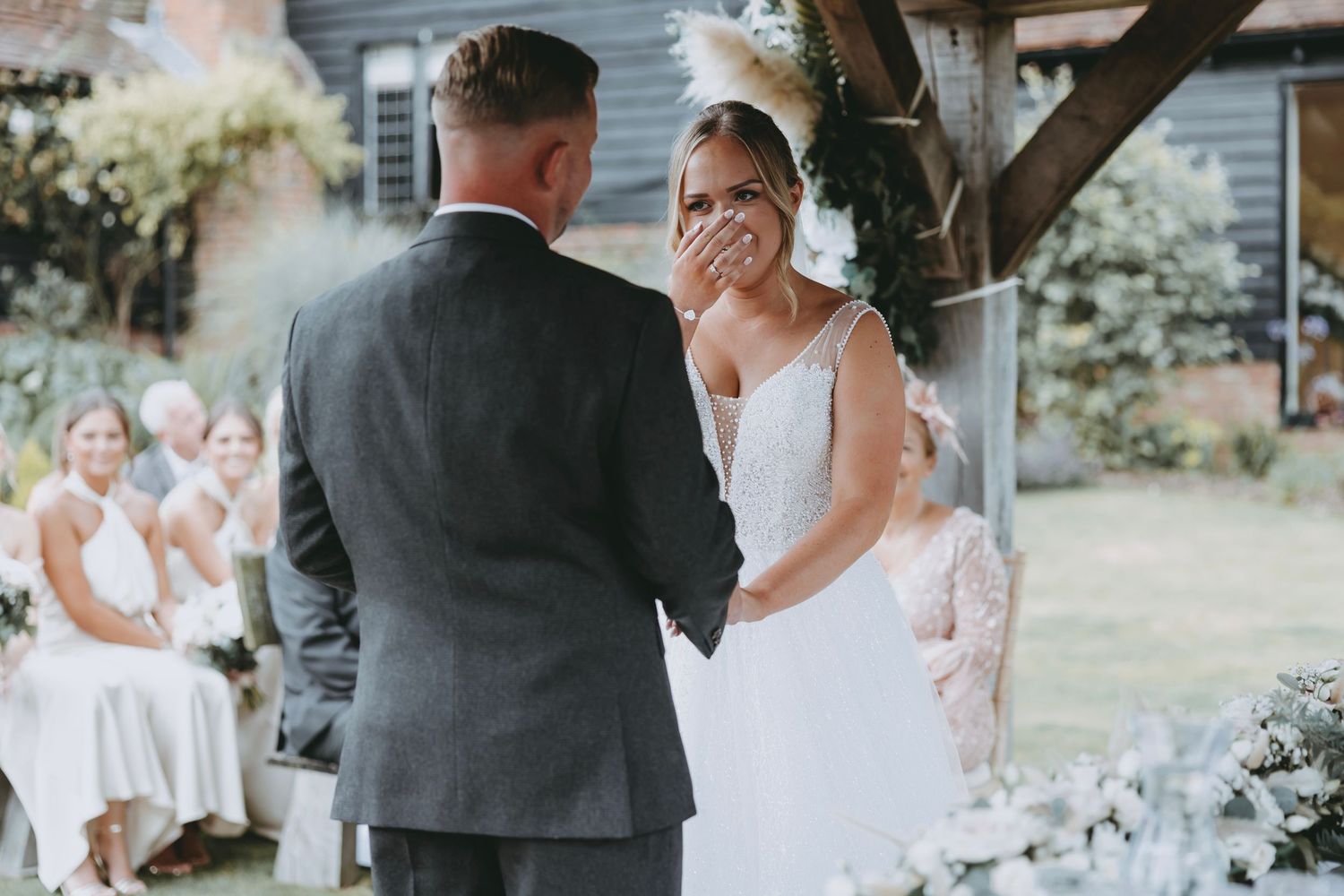 Outdoor wedding ceremony with white flowers and natural garden backdrop.