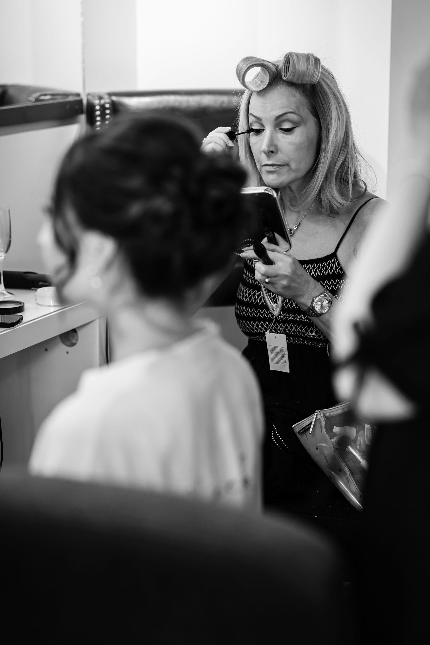 Black and white photo of wedding party getting ready with hair styling.