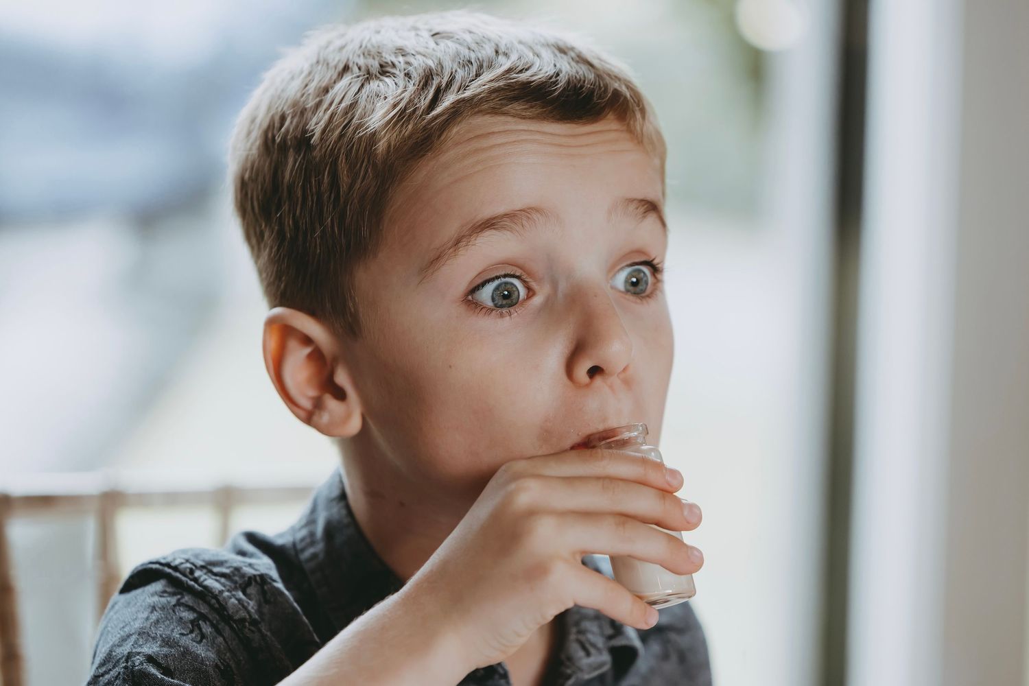 Person covering their mouth with hand while seated indoors.