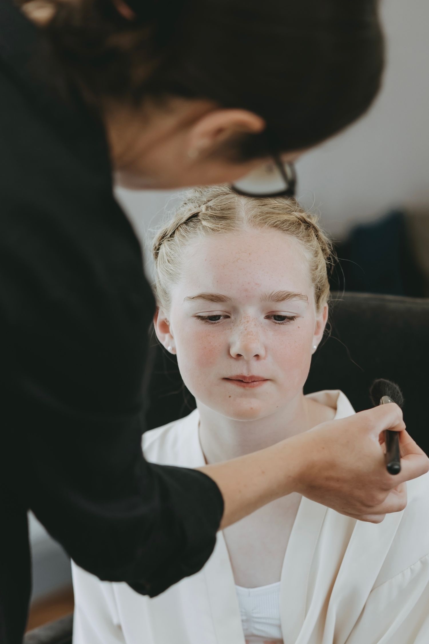 Close-up shot of makeup being applied with a brush during bridal preparations.
