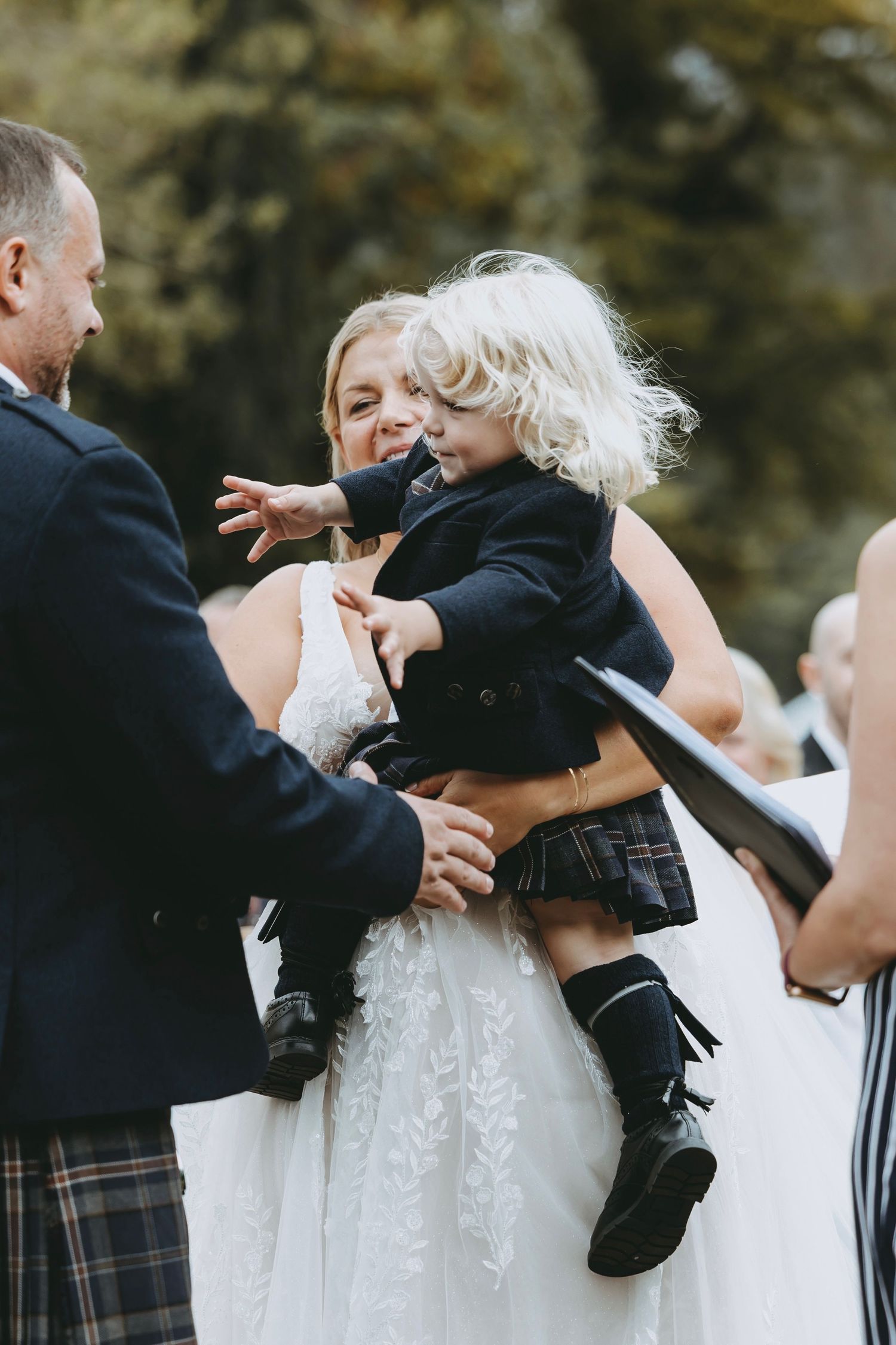 Wedding couple embracing while wearing traditional Scottish formal attire with kilts.