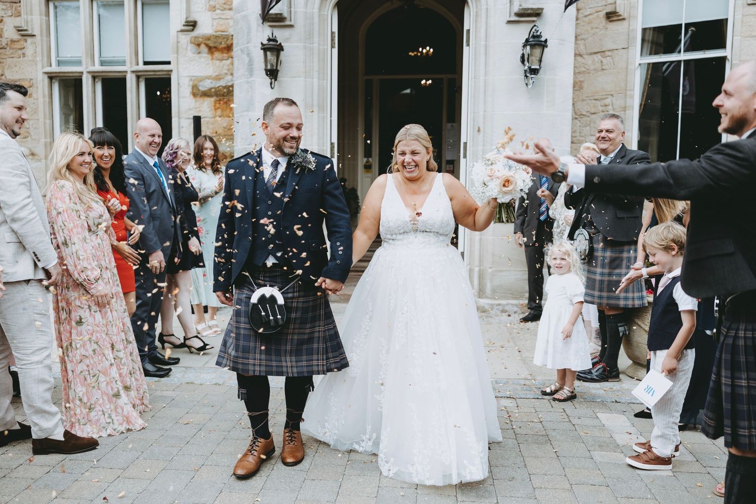 Wedding guests gather outside a stone building for a celebration at Crossbasket Castle.