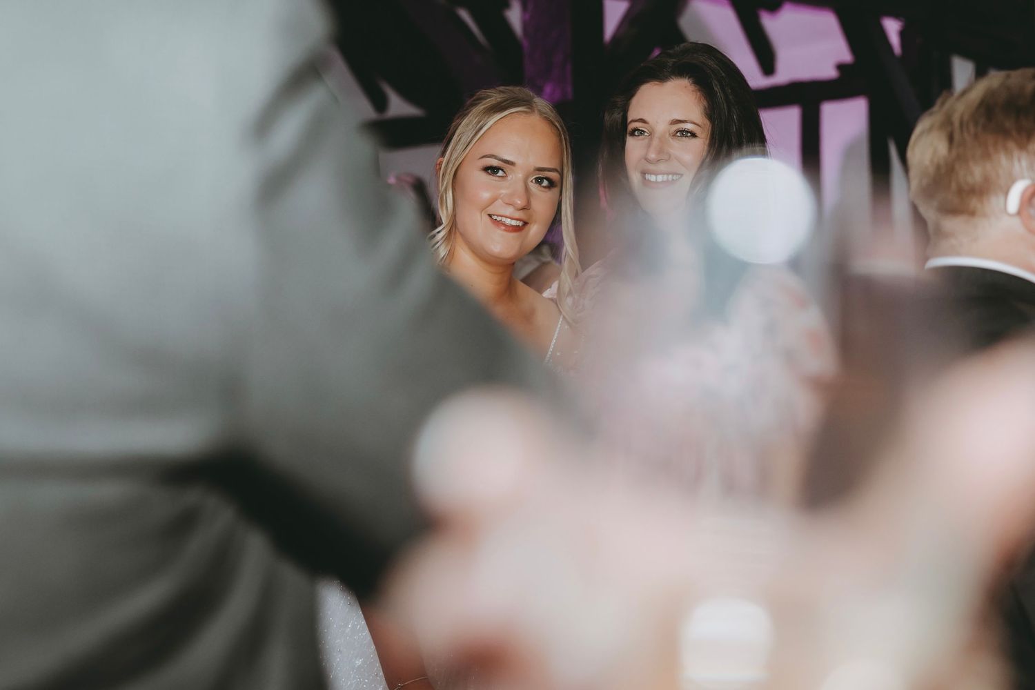 Wedding reception guests enjoying a lively celebration with colorful lighting and decor.