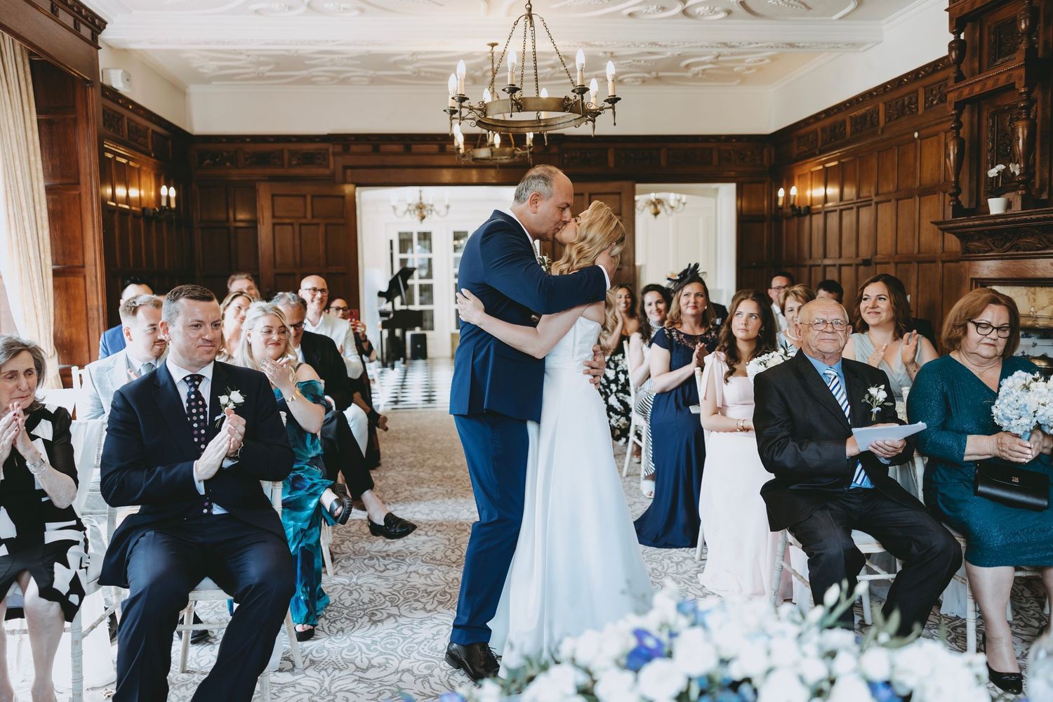 Wedding guests dance together on a rustic wooden dance floor during an evening reception celebration.