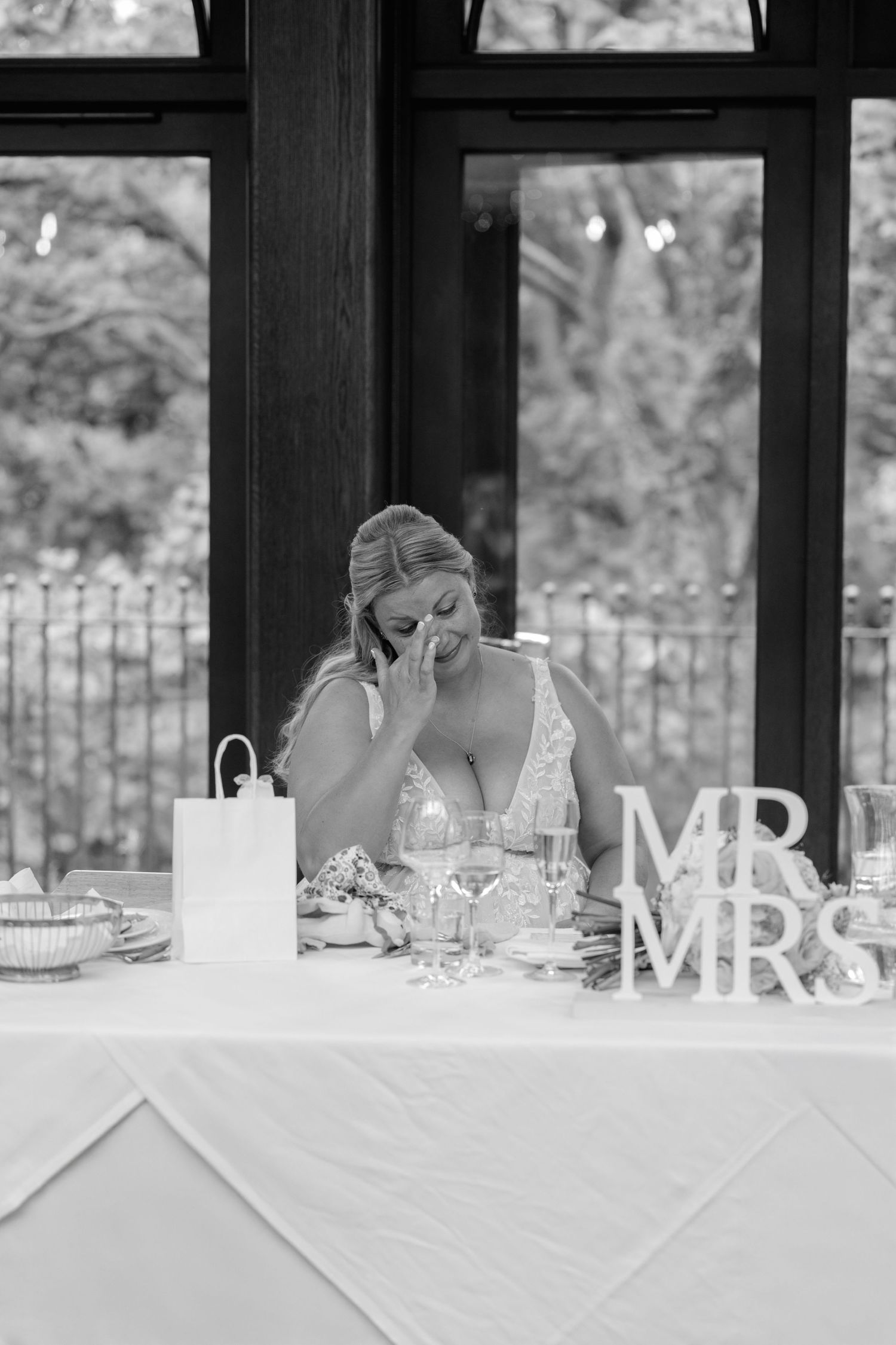 Black and white photo of emotional moment at wedding reception table.
