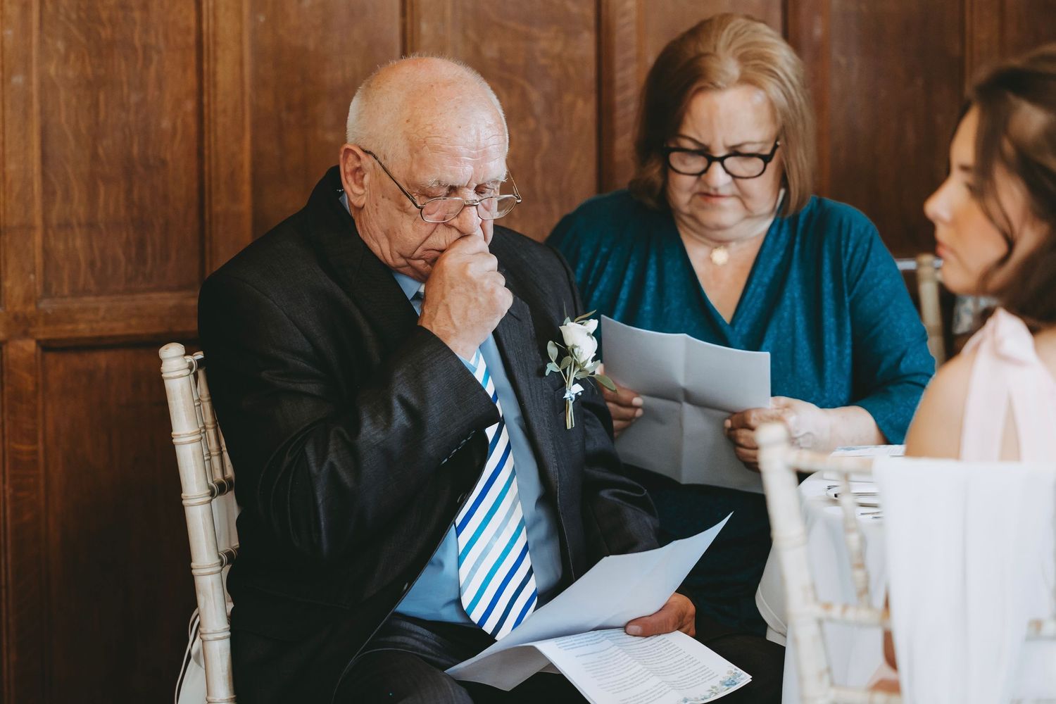 Wedding guests at head table listening intently during reception speeches.