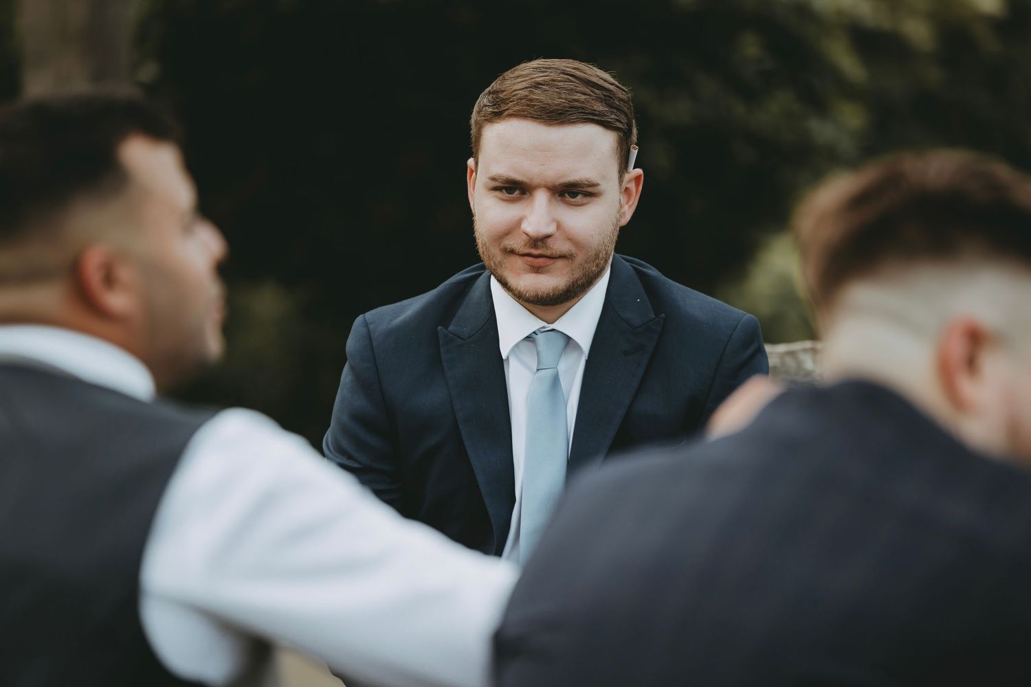 Guests in formal attire gather at an outdoor wedding celebration.