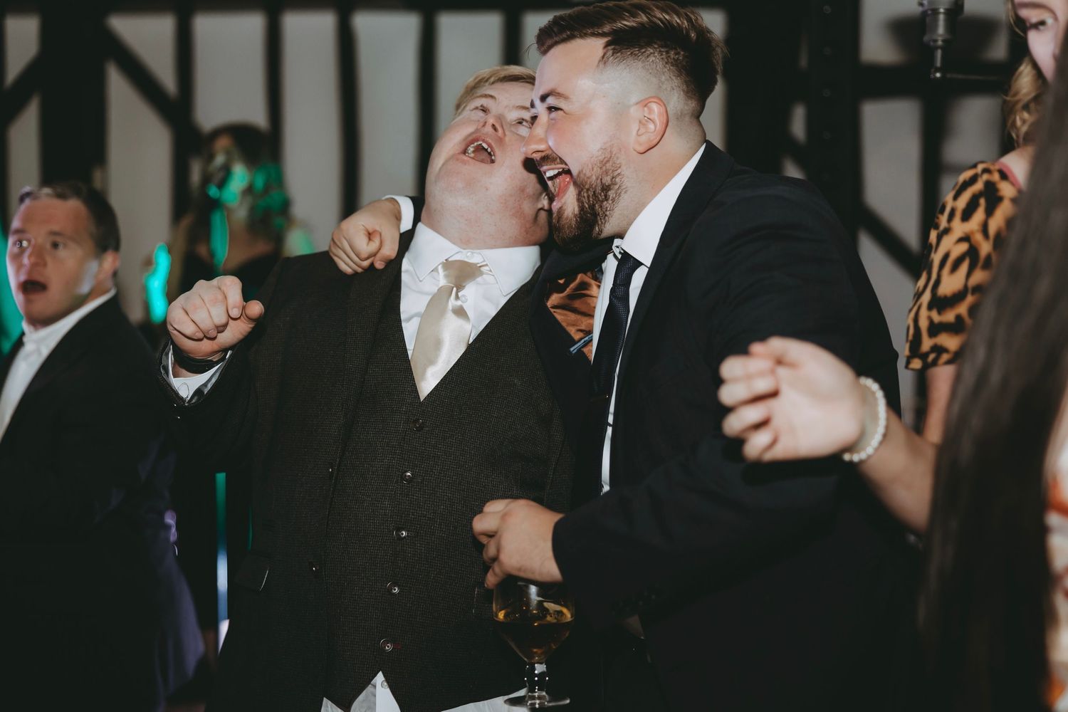 Joyful celebration with guests dancing and laughing at wedding reception.