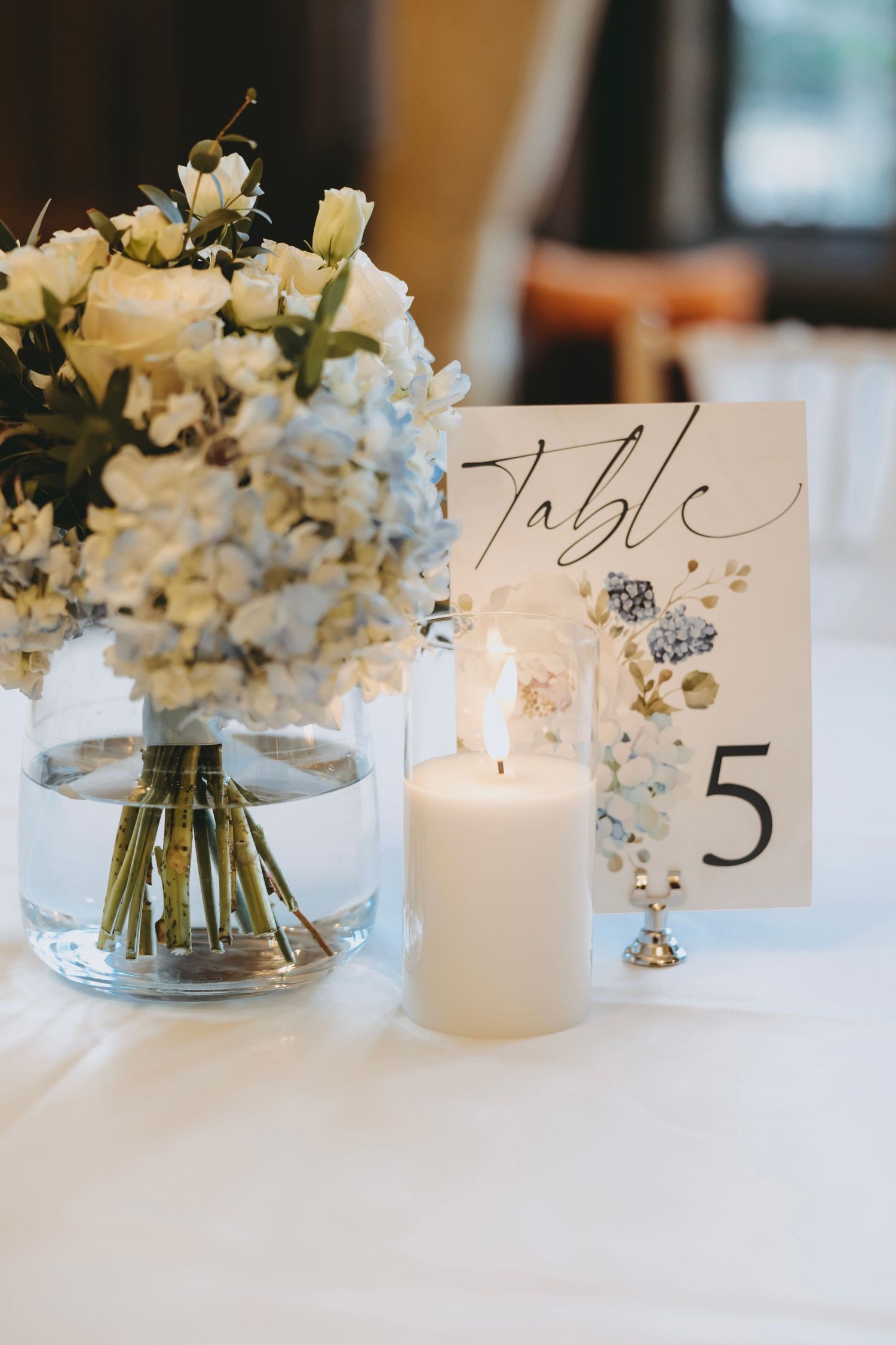 Wedding reception table numbers and white flower arrangements on crisp white linens.
