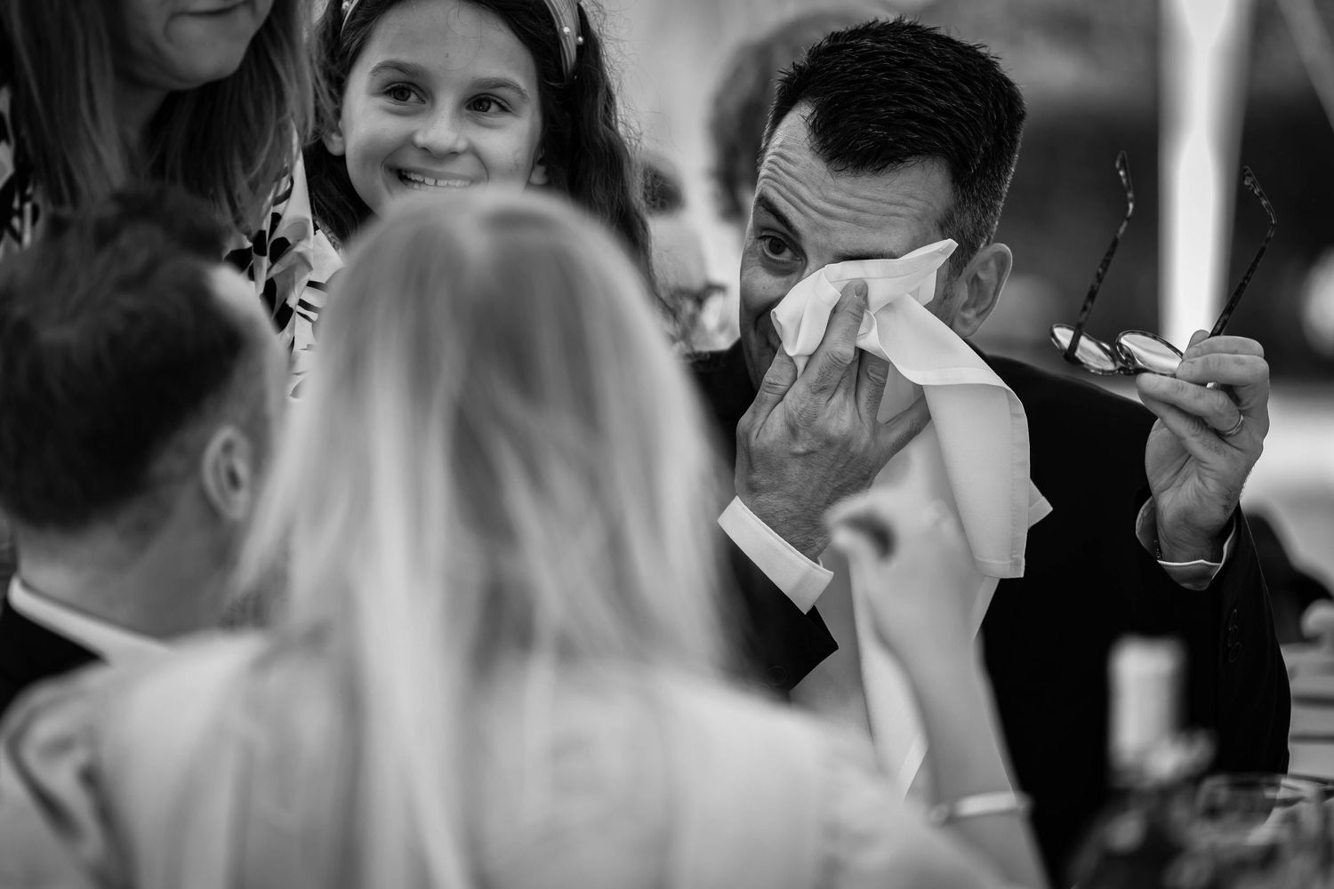 Emotional moment captured during wedding ceremony as guest wipes tears.