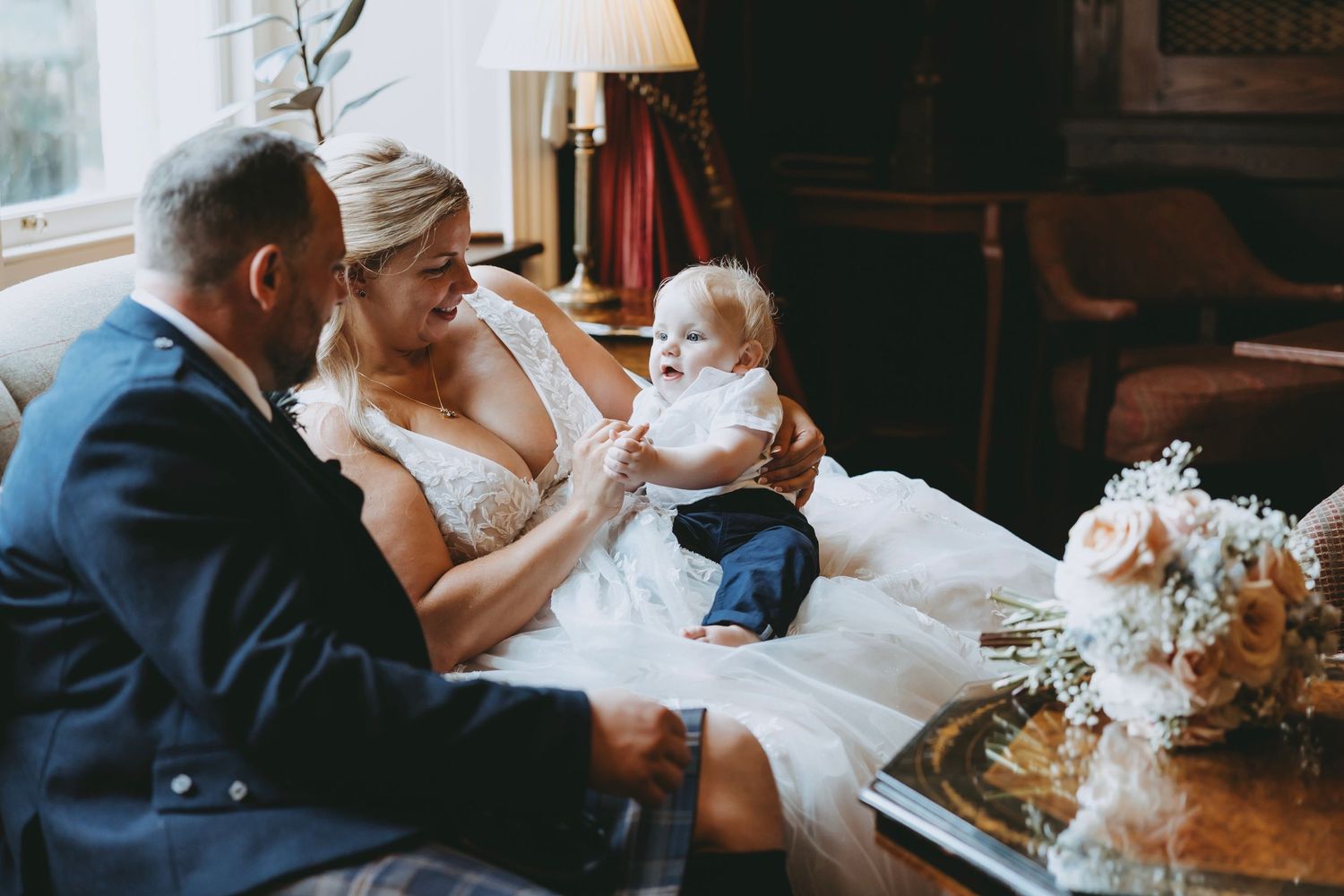 Wedding guests share intimate moments on a couch during a reception celebration.