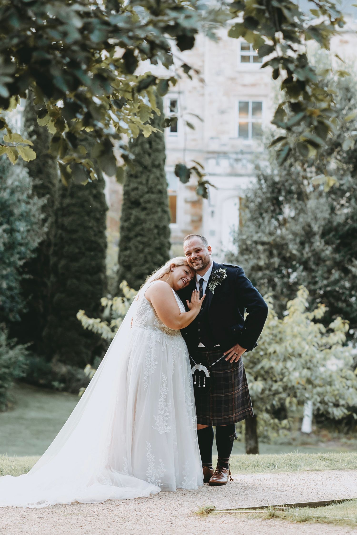 Candid wedding photos showing tender moments between newlyweds in a garden setting at Crossbasket Castle, Scotland.