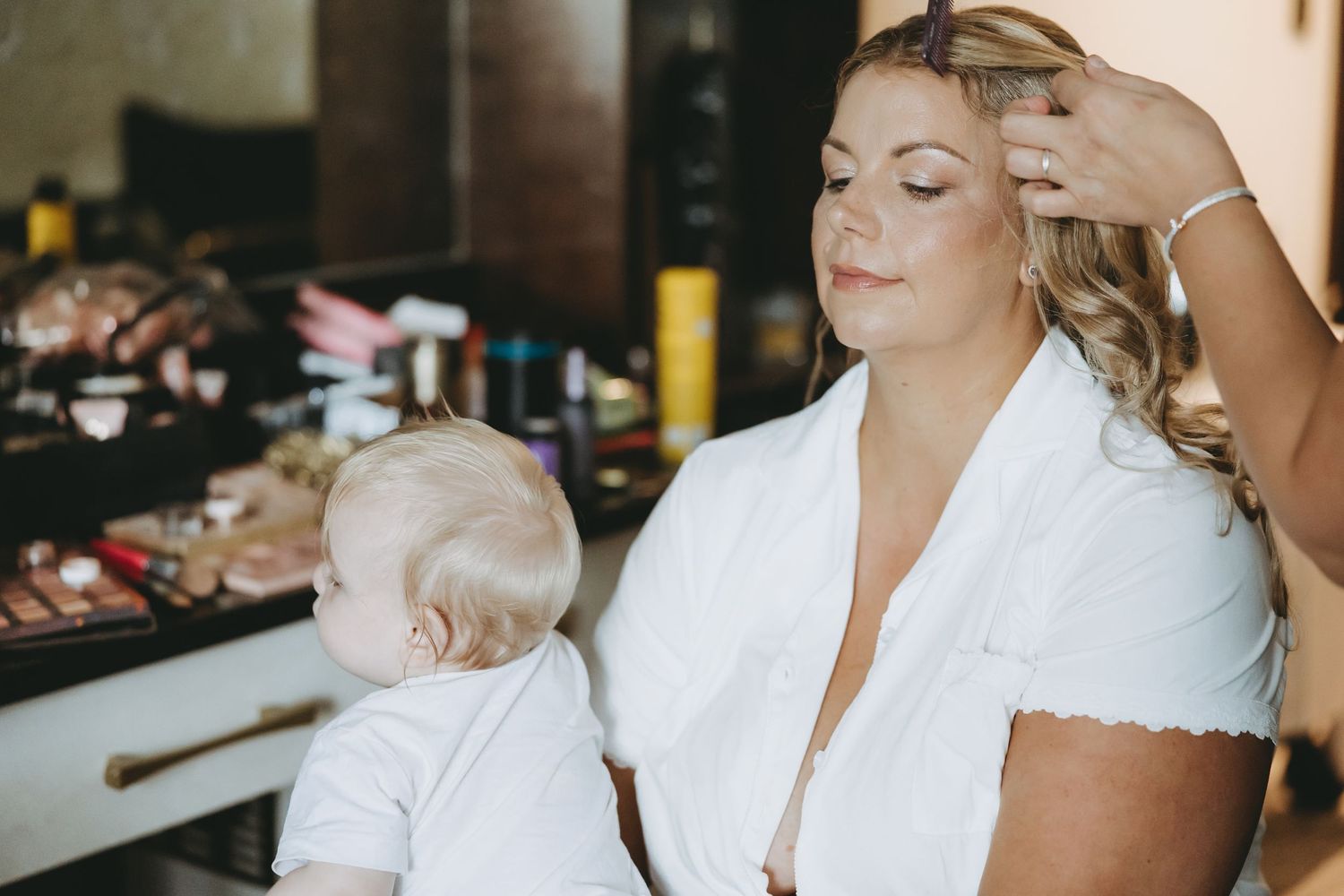 Wedding preparation scene showing styling and makeup application.