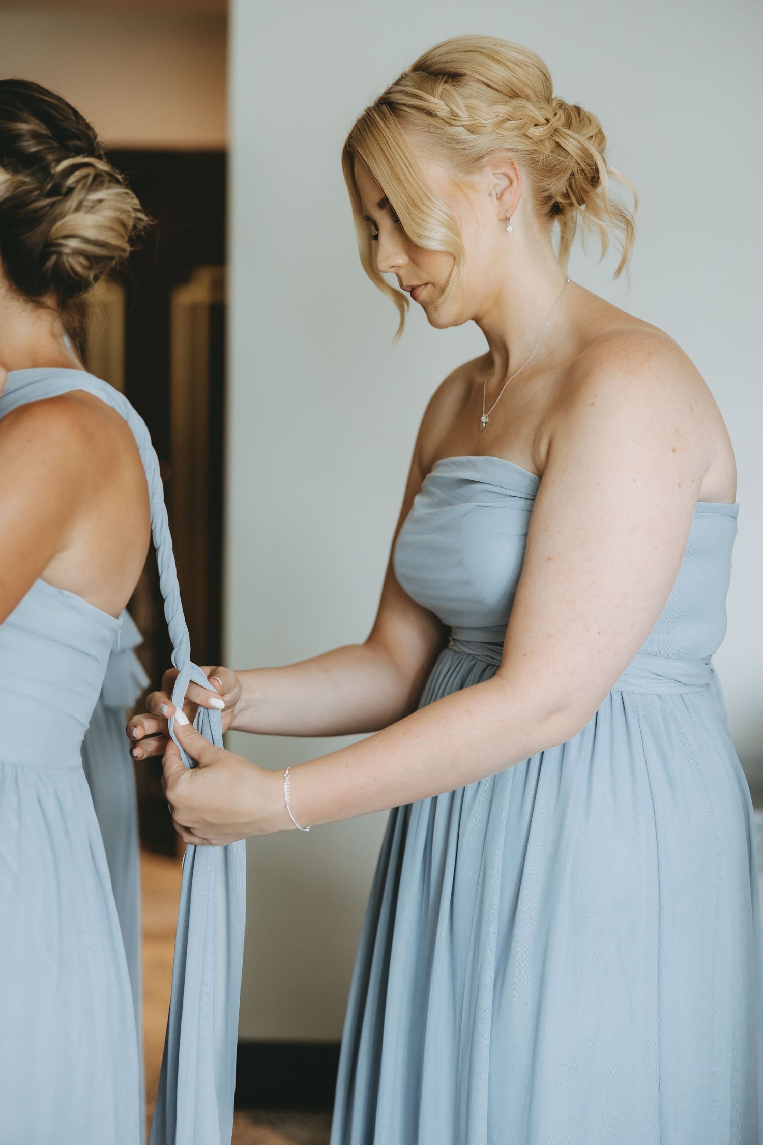 People in pale blue dresses adjusting their formal attire.