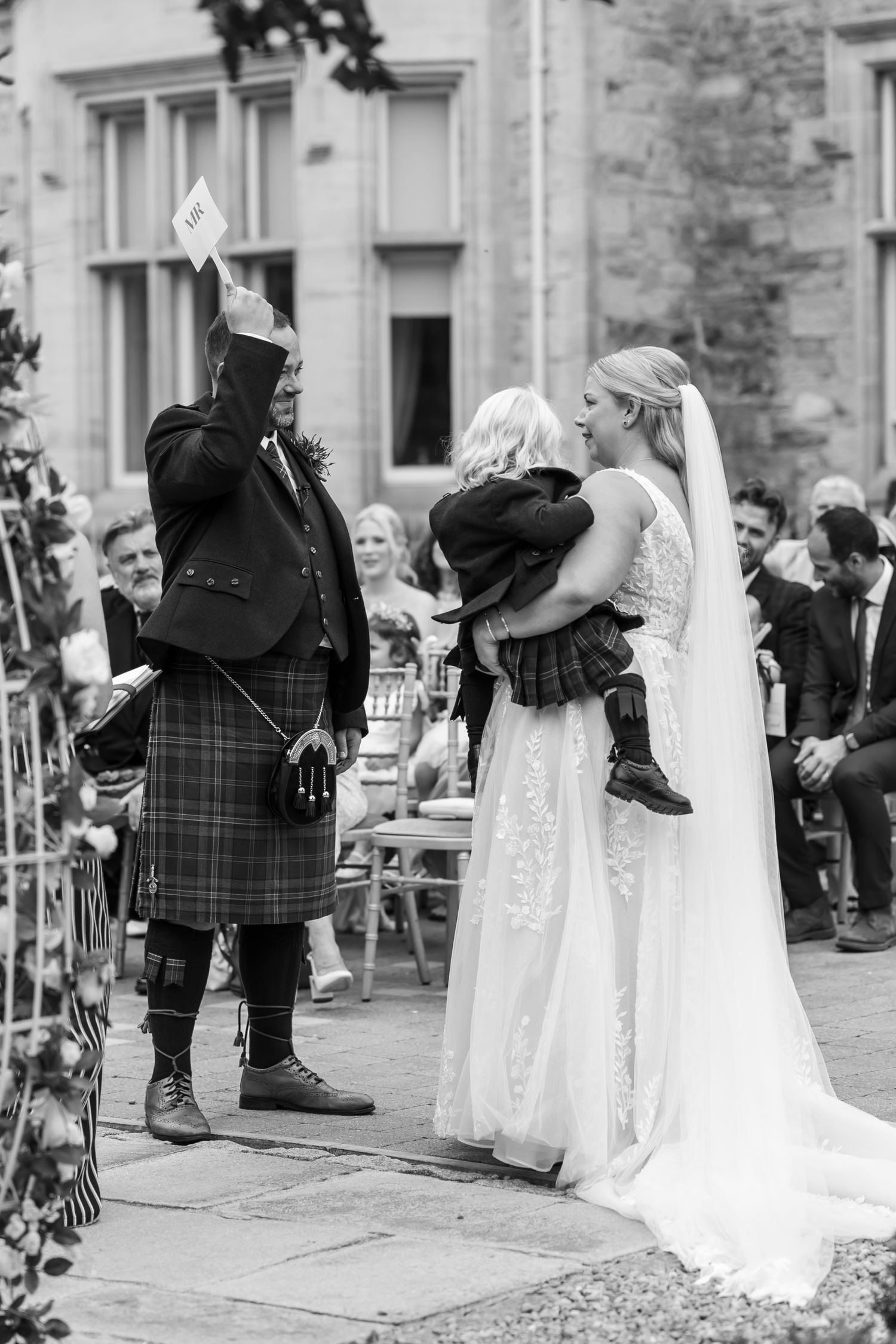 Black and white photo of wedding ceremony moments with Scottish kilts and white dress.