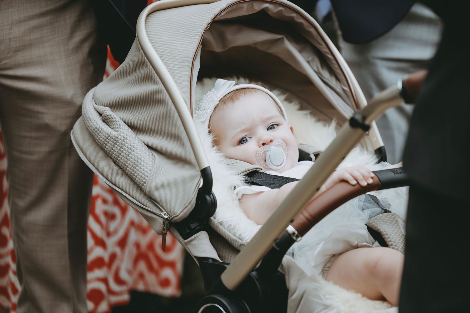 Close-up view of an infant in a beige stroller looking upward.