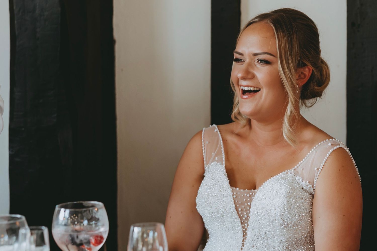 Guests share joyful moments during wedding reception speeches in an elegant venue.