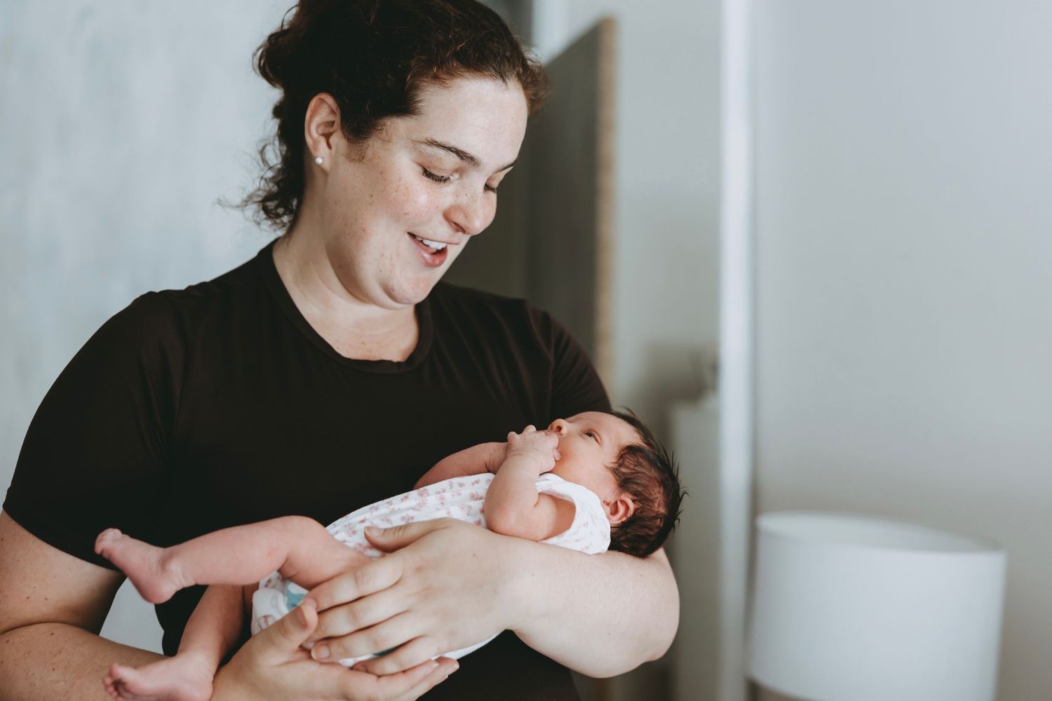 A series of tender moments between a parent and newborn baby in a minimalist white setting.