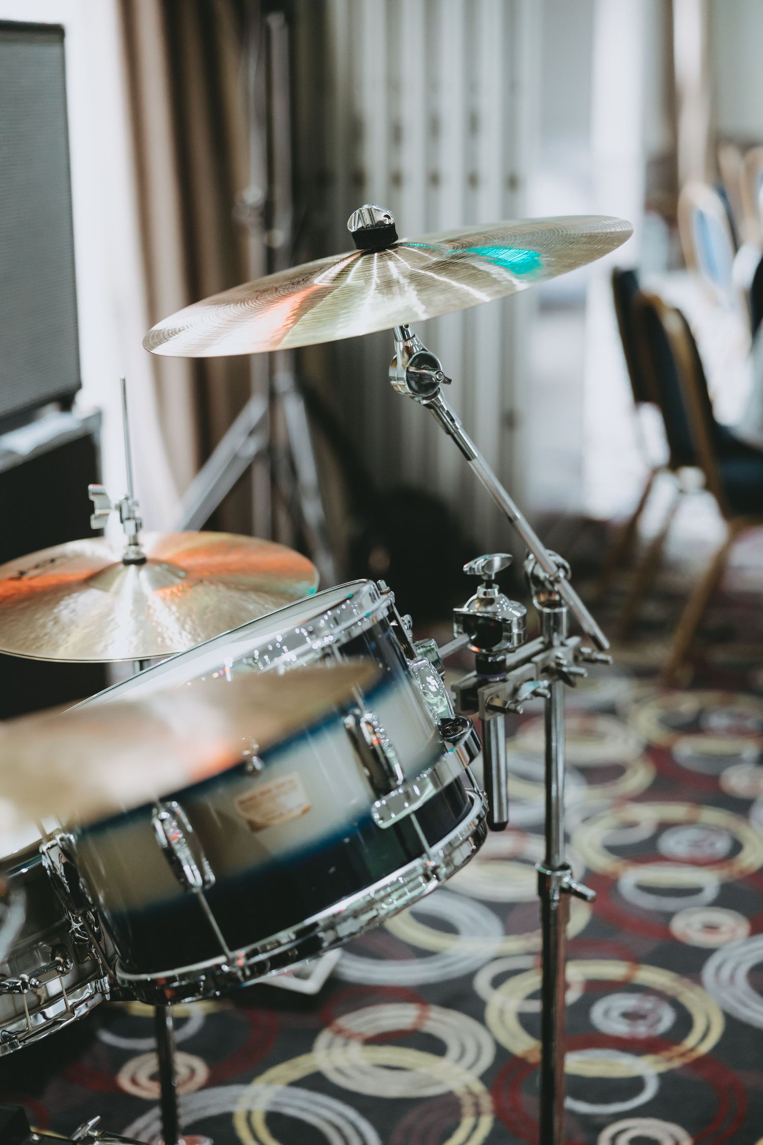 Close-up view of a professional drum kit with cymbals and hardware on a patterned carpet in a studio setting.