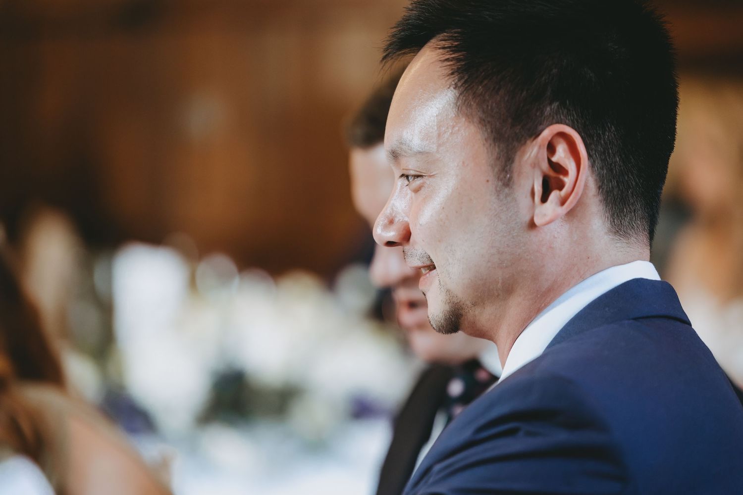 Wedding guests seated at elegantly set tables in formal attire.