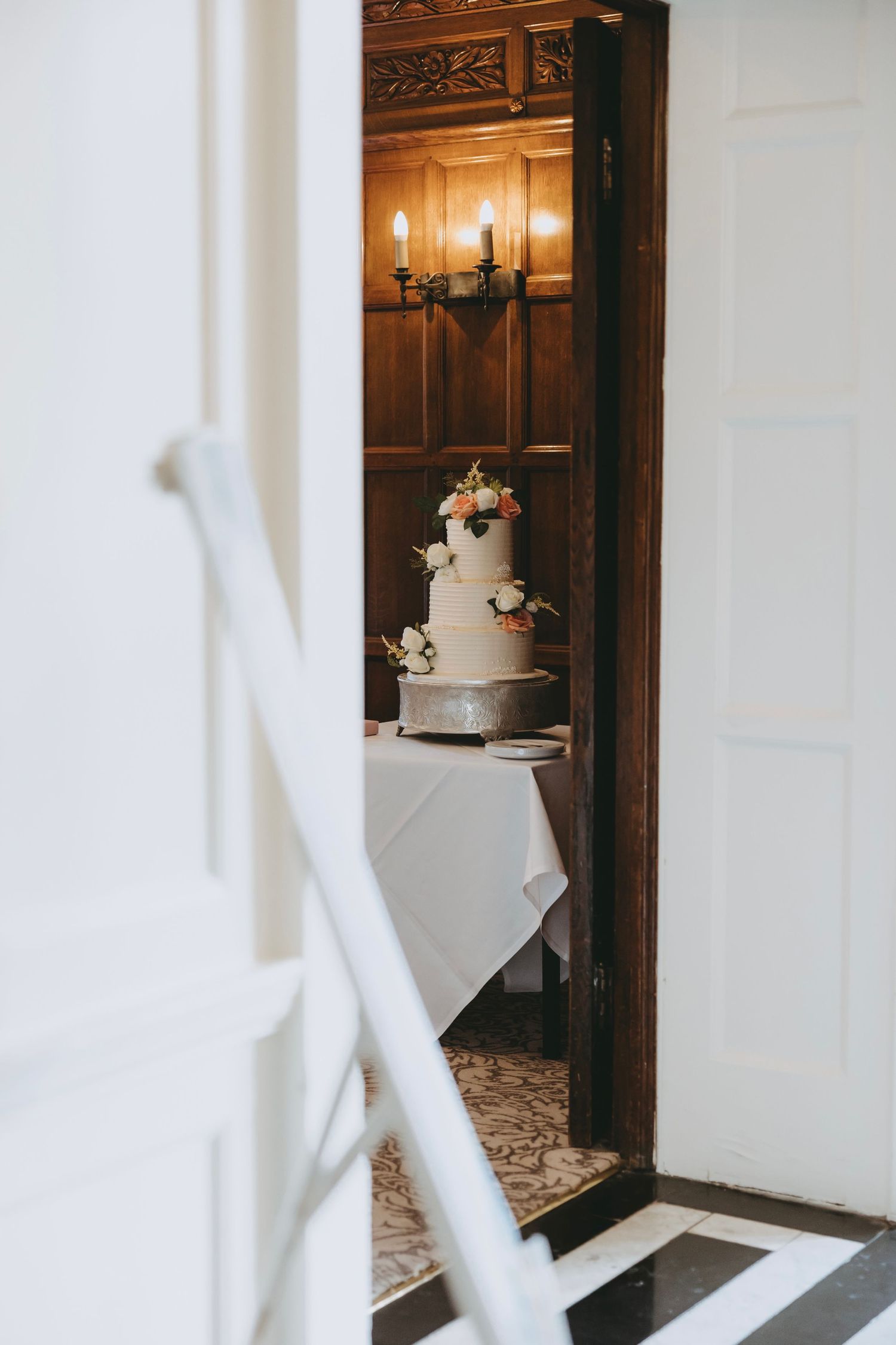 White hallway with wooden doors leading to a wedding reception area.