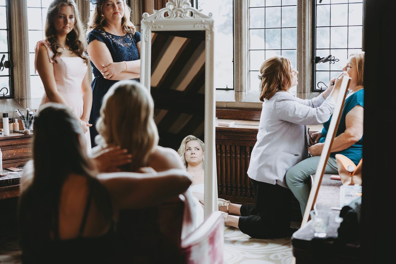 Wedding party gathered by large windows in an elegant vintage room.