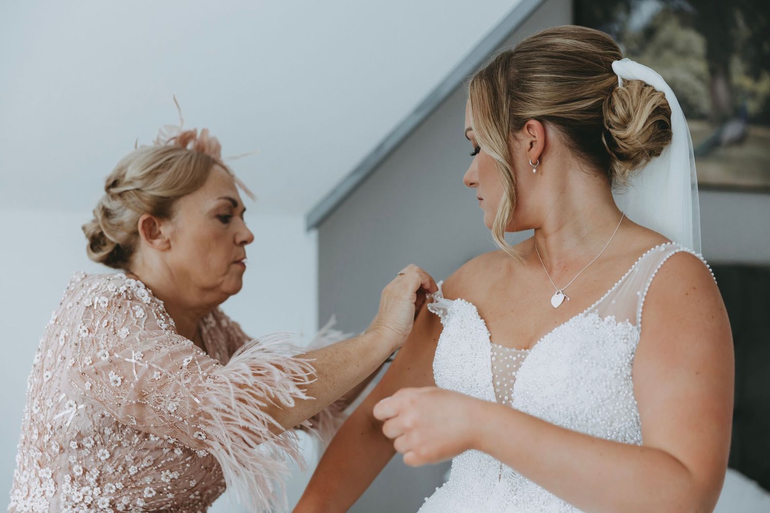 Final adjustments being made to a bride's necklace and dress before the ceremony.