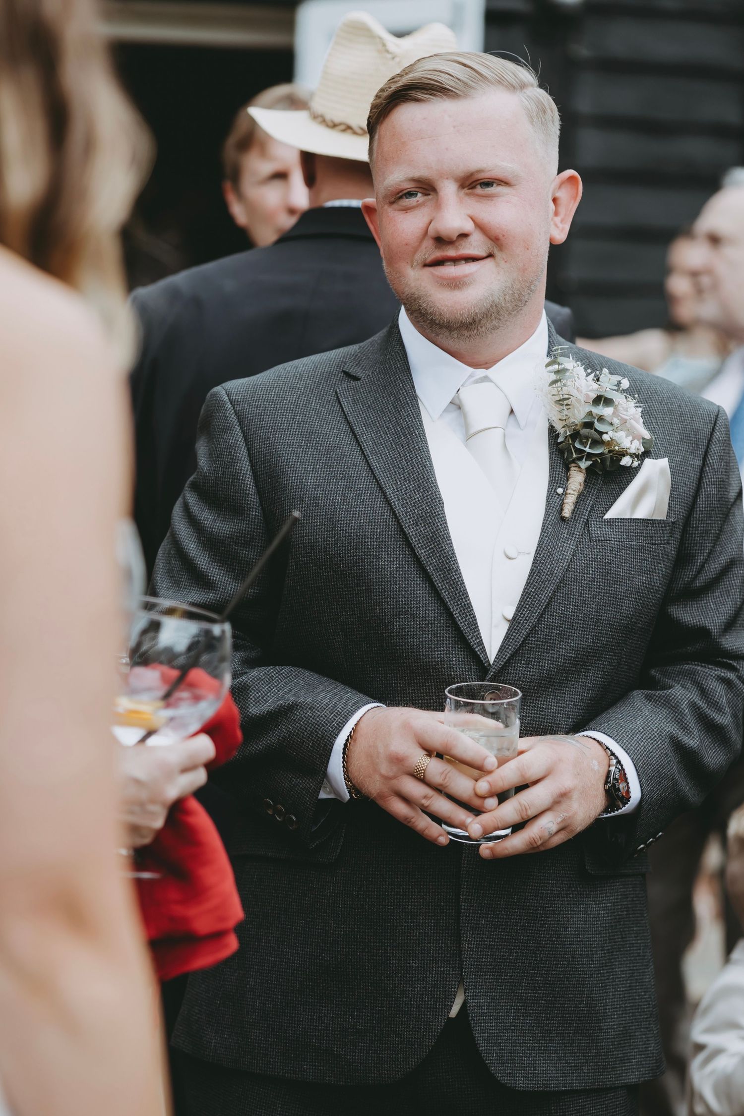 Wedding guests in formal attire enjoying drinks during an outdoor reception.