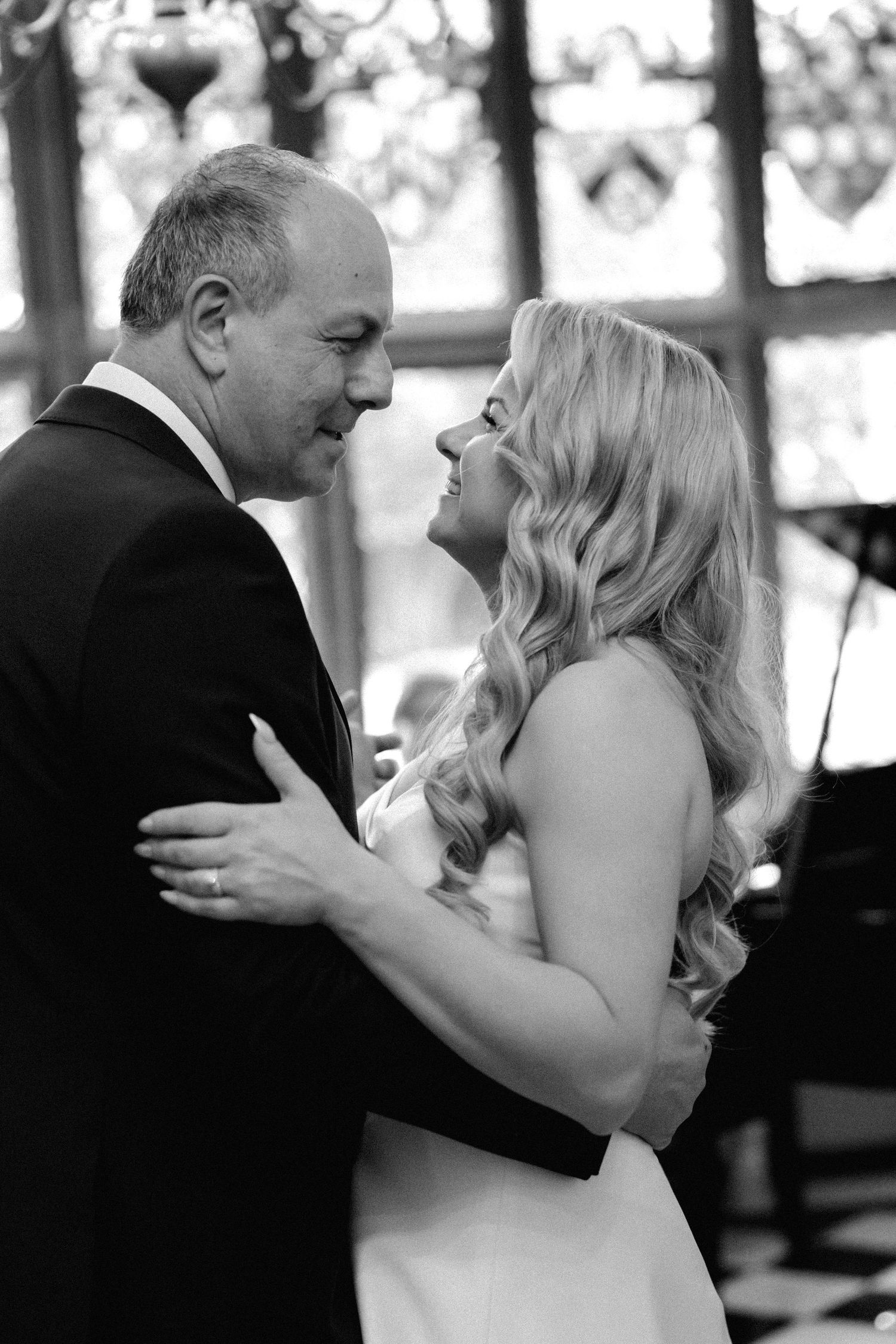 A black and white photo captures a tender dance between two people at their wedding at Fanhams Hall, Ware, Hertfordshire