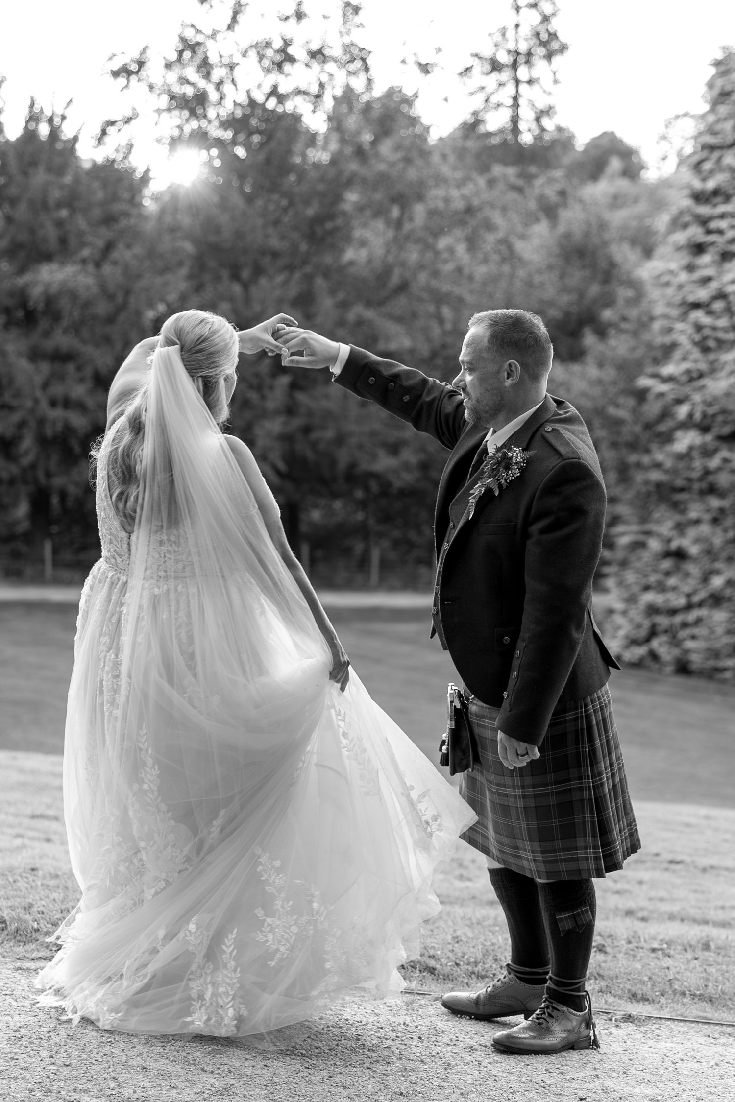 Black and white wedding photos showing a couple walking together on a grassy hill at dusk.