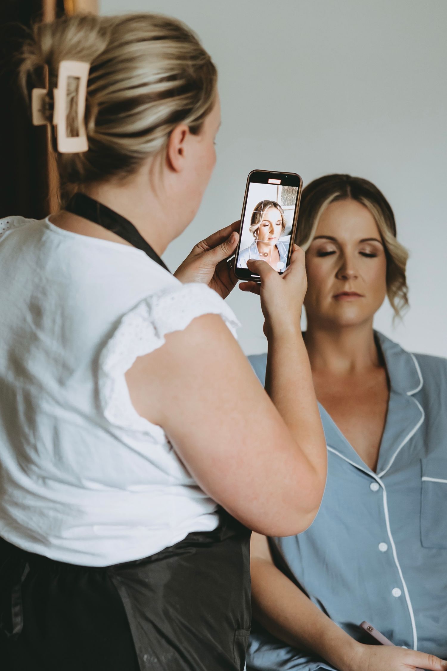 Someone taking photos with a phone during a makeup application session.