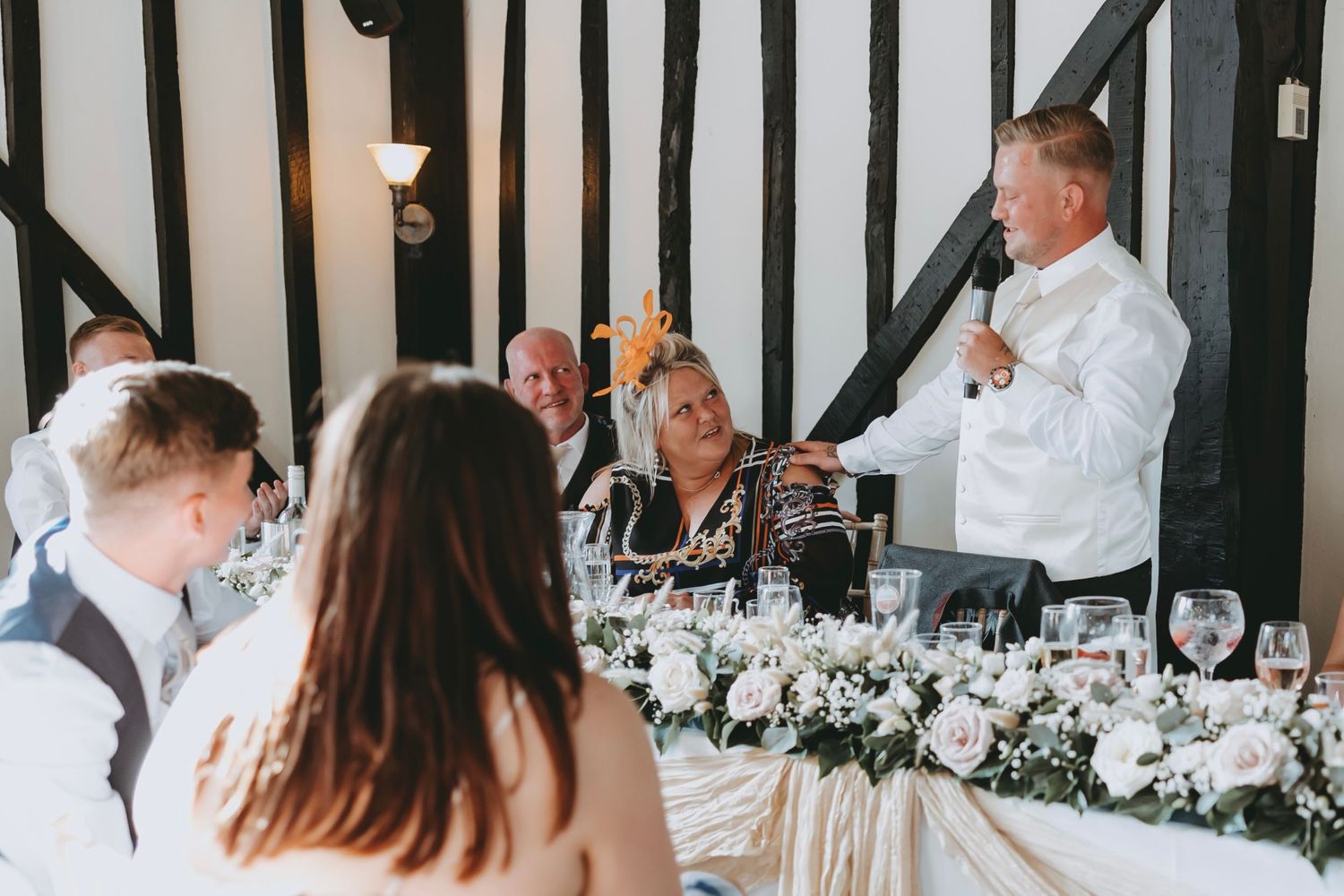Wedding celebration in progress with guests seated at decorated tables in rustic venue.