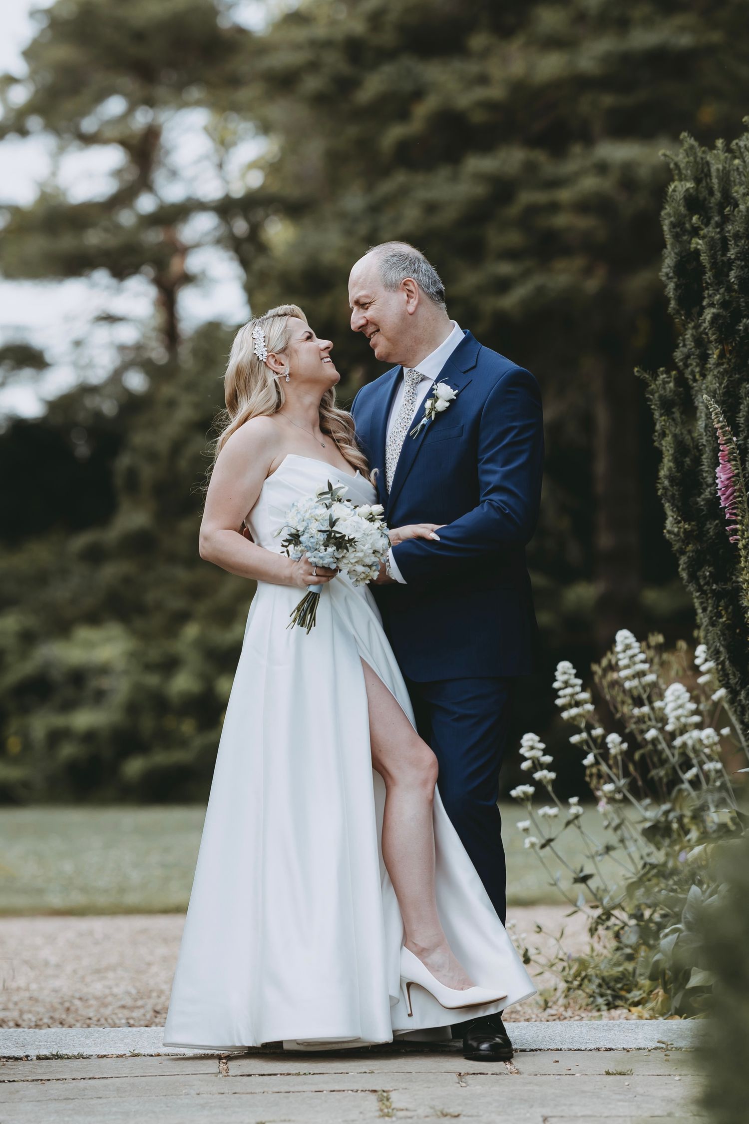 Wedding couple shares intimate moments near decorative garden gates and flowers.