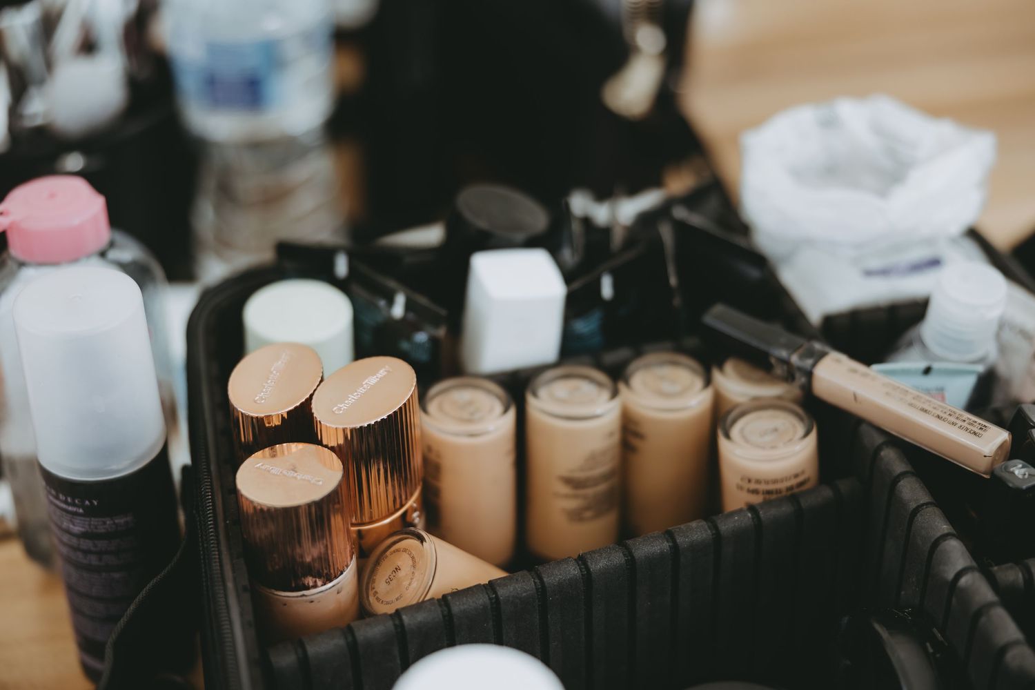 Collection of makeup foundation bottles and cosmetics arranged in a professional styling kit.