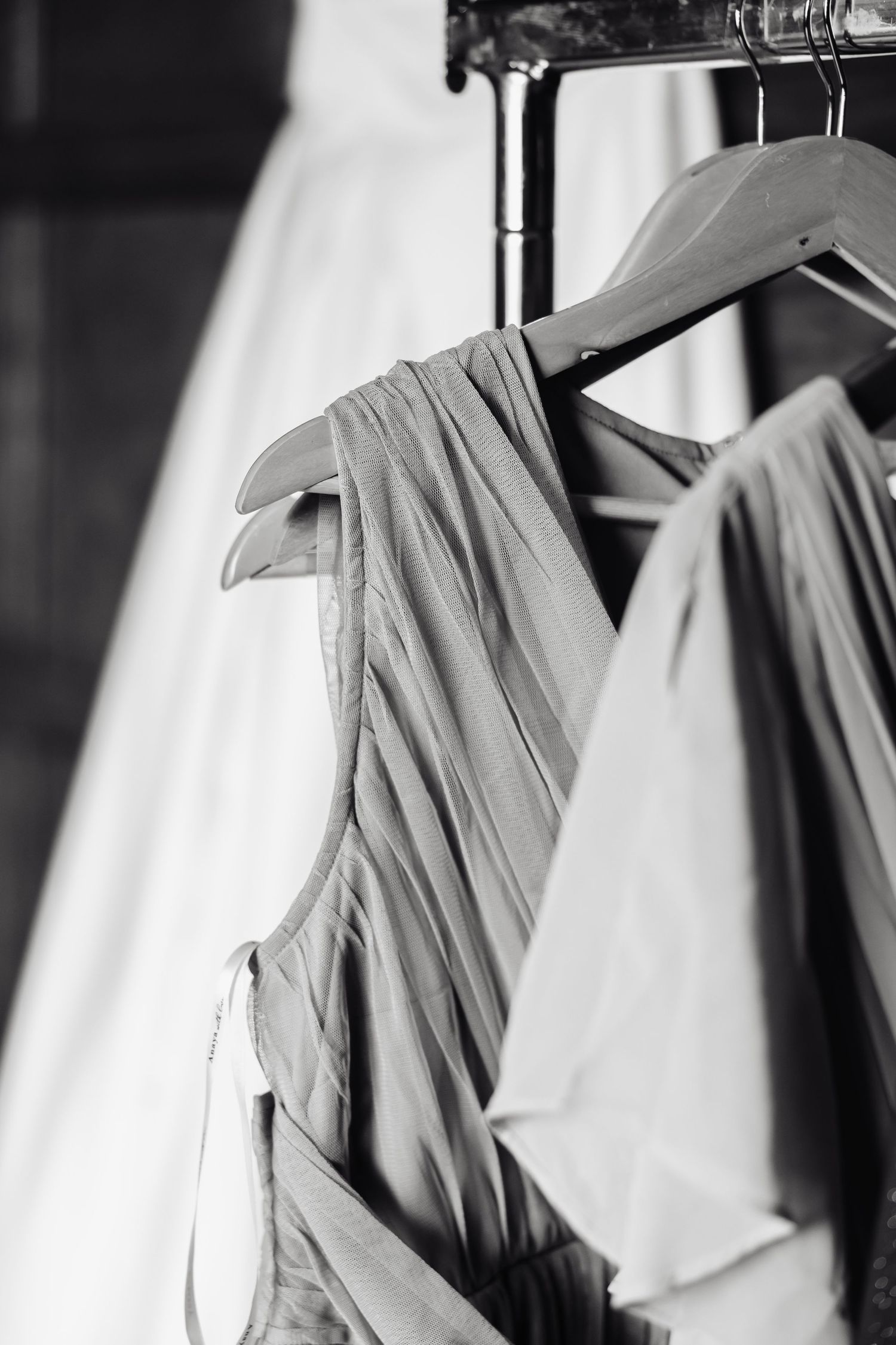 White and gray dress shirts hanging neatly on hangers in a closet.