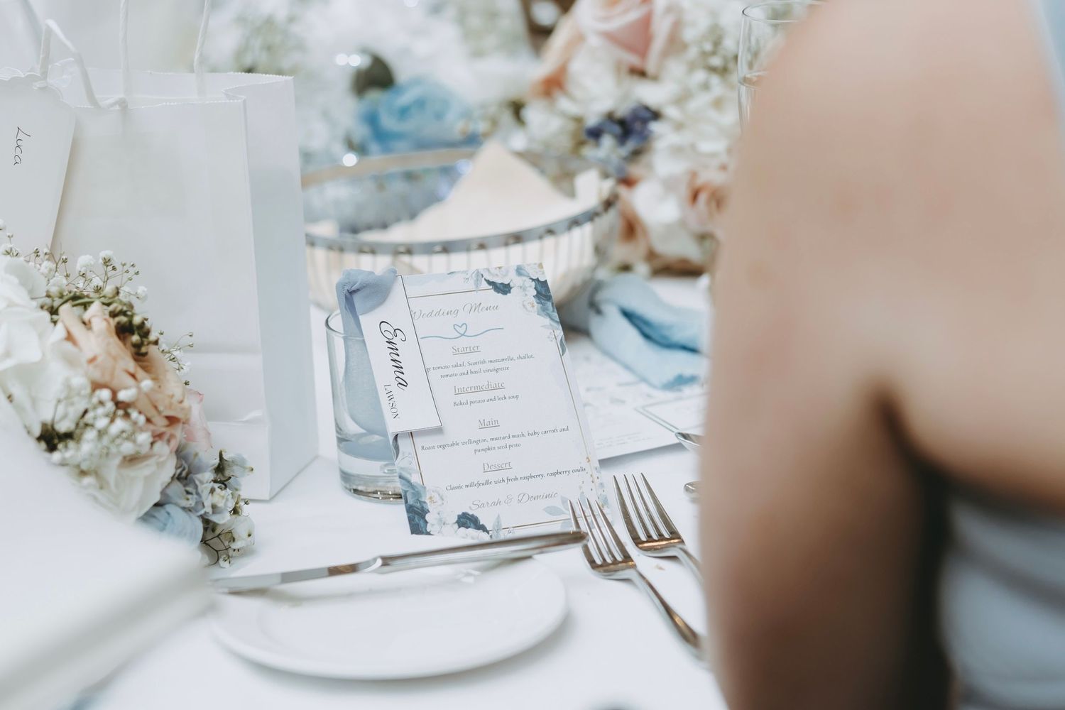 Close-up of formal place settings with white linens and delicate floral arrangements.