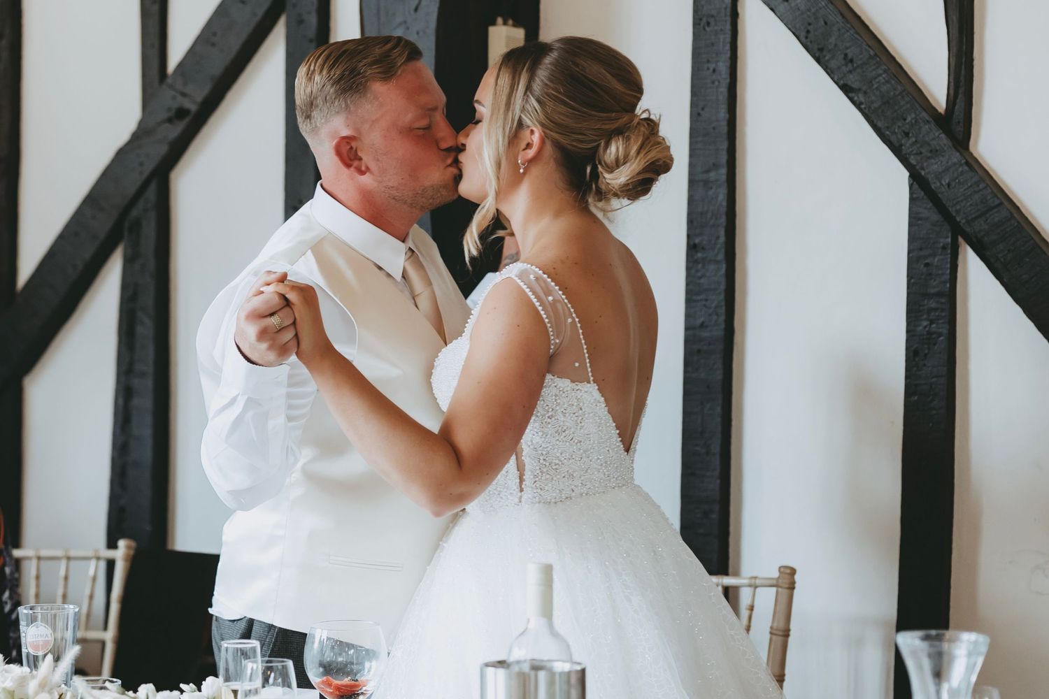 Wedding couple dancing together in an elegant timber-framed venue.