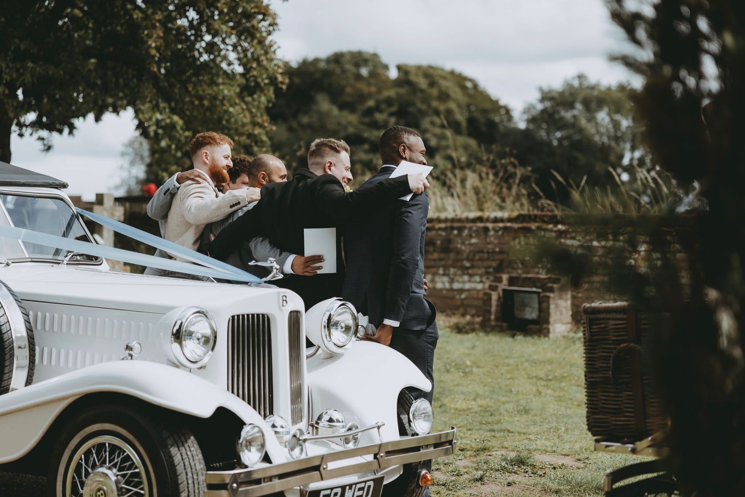 Classic vintage cars lined up at an outdoor wedding venue.