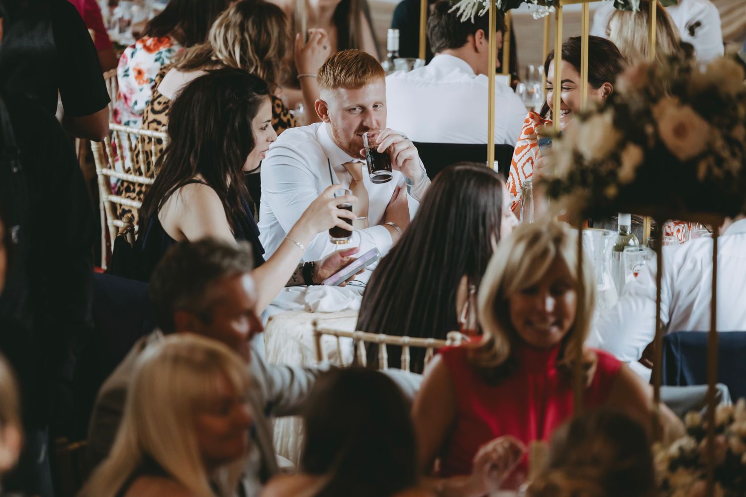 Wedding guests mingling during reception dinner under soft lighting.