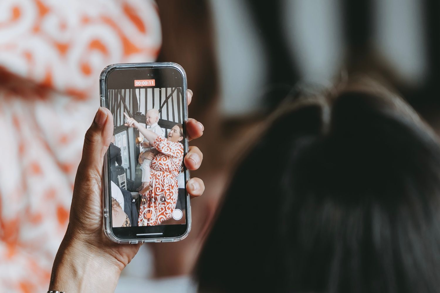 Someone holding up a phone displaying a photo during an event.